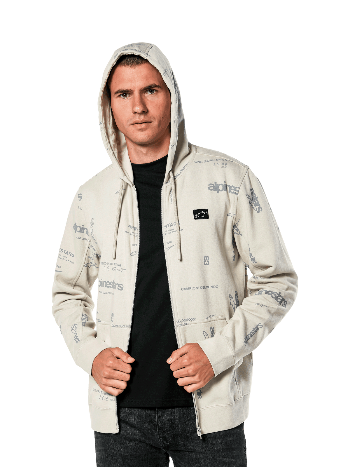 Felpa con cappuccio Alpinestars Plenitude, abbigliamento sportivo casual, felpa Off White con zip frontale e grafiche grigie all-over, indossata da un uomo con il cappuccio alzato sopra una maglia nera, con piccola patch del logo sul petto e tasca a marsupio
