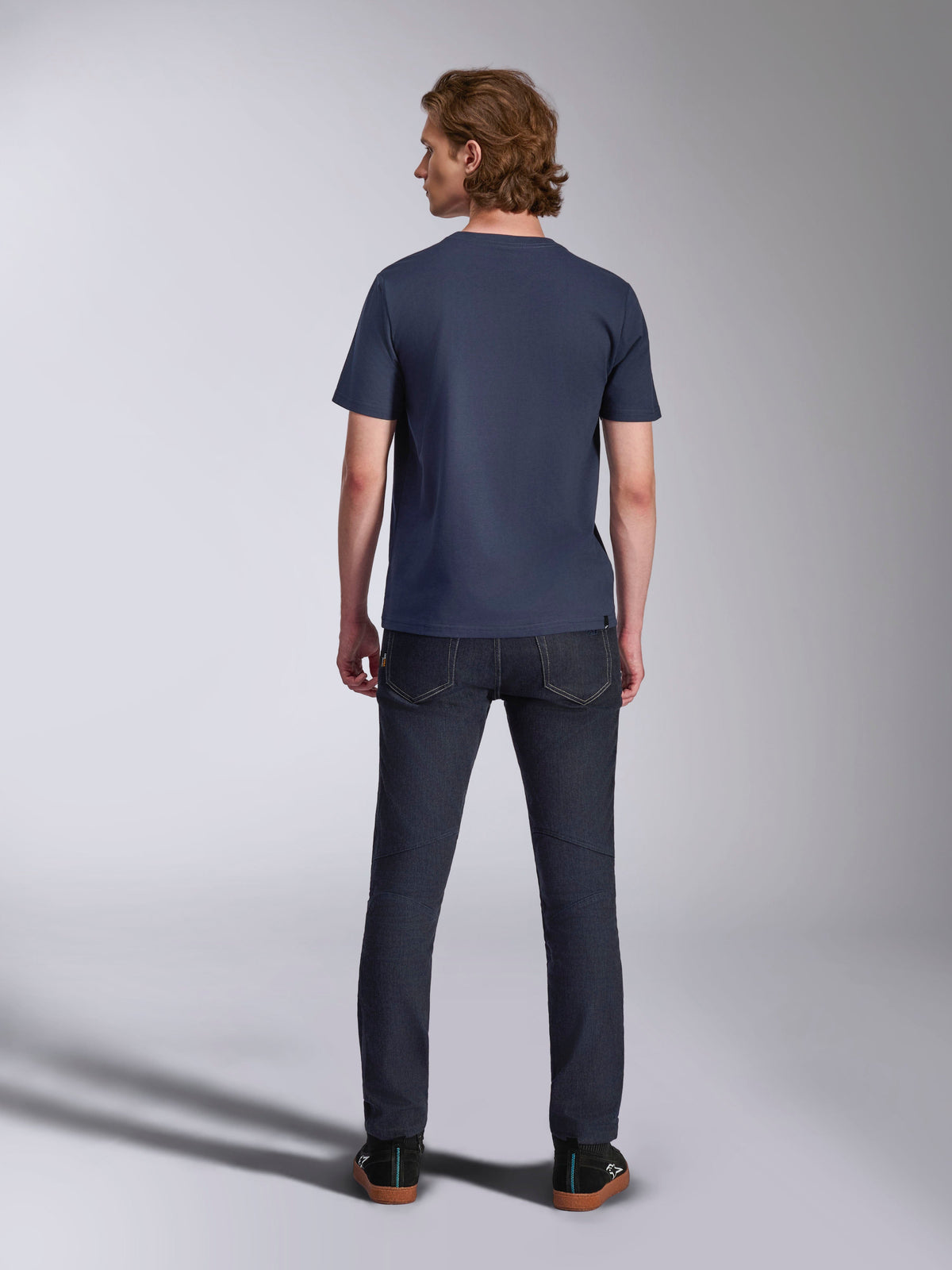 Alpinestars Ageless 2.0 CSF Tee, t-shirt a maniche corte, blu navy, vista posteriore, indossata da un uomo con jeans in denim scuro e sneakers nere, streetwear casual ispirato al motorsport