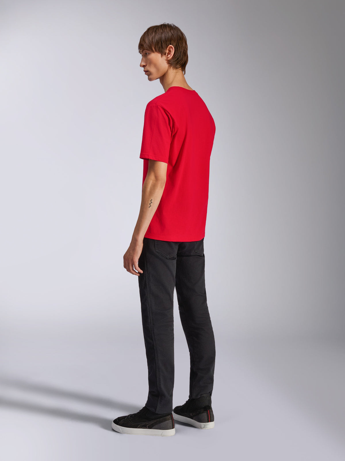 Alpinestars Ageless Shadow CSF Tee, maglietta a maniche corte, rosso, vista posteriore su modello, indossata con pantaloni neri e sneakers, streetwear casual ispirato al motorsport