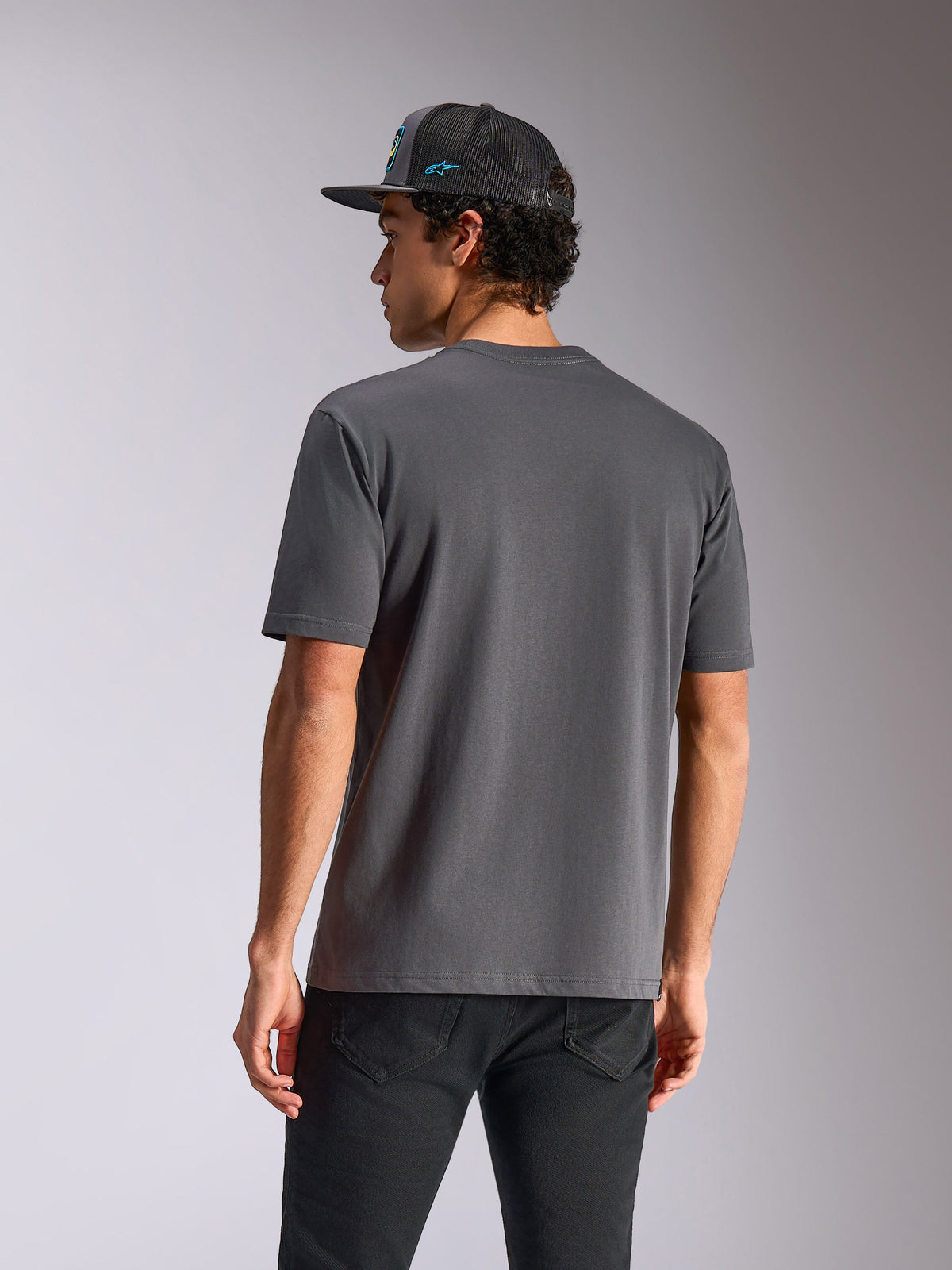 Alpinestars Blaze 2.0 CSF Tee, t-shirt a maniche corte, grigio antracite, vista posteriore, indossata con jeans neri e un cappellino in mesh, streetwear casual ispirato al motorsport