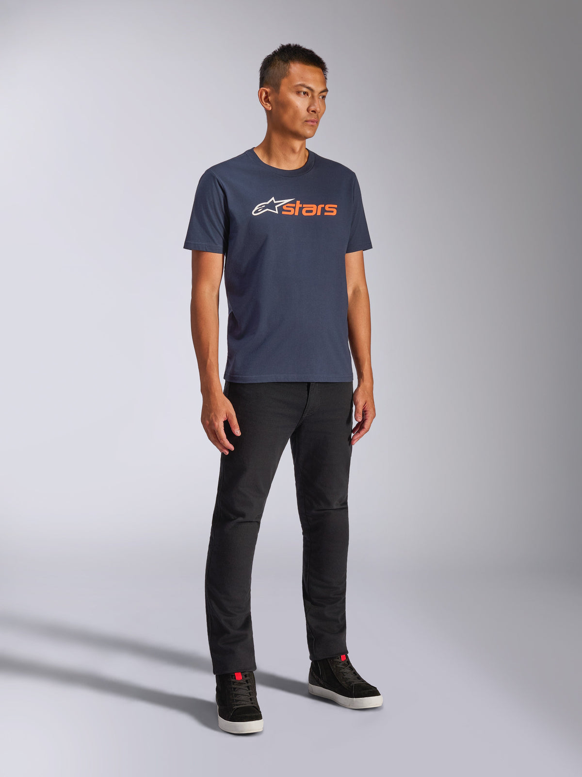 Alpinestars Blaze 2.0 CSF Tee, maglietta a maniche corte, blu navy con logo Blaze bianco e arancione, indossata da un modello con pantaloni neri e sneakers, streetwear casual ispirato al motorsport