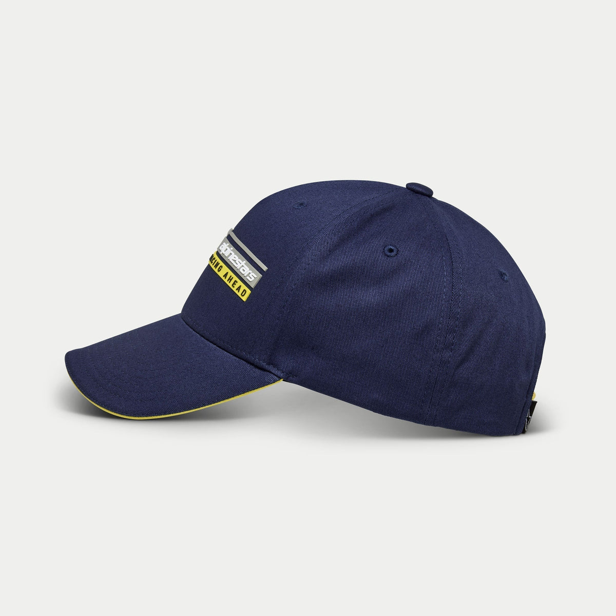 Cappello Alpinestars Par, cappellino da baseball blu navy, vista laterale, corona strutturata con visiera curva e dettaglio sandwich giallo, ricamo 3D del logo lineare Alpinestars Racing Ahead, copricapo casual ispirato al motorsport