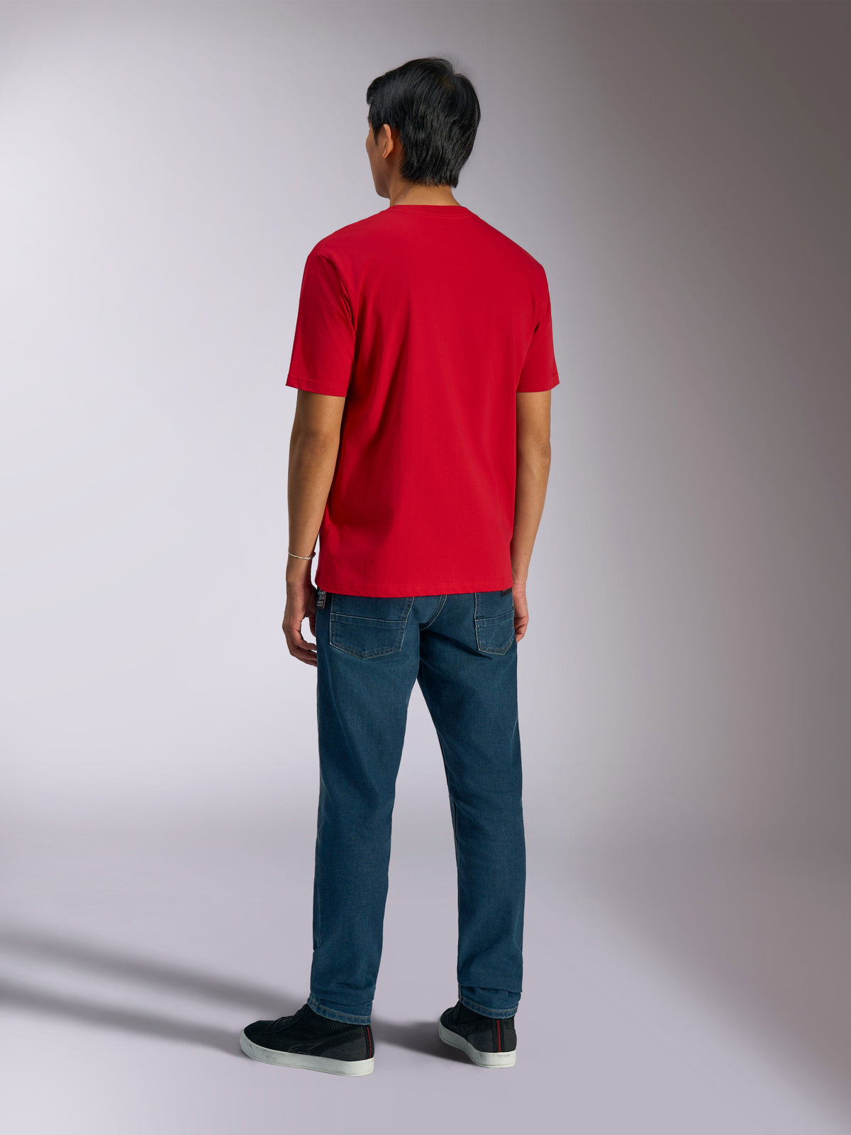 Alpinestars Ageless Shadow CSF Tee, t-shirt a maniche corte, rosso, vista posteriore indossata da un modello con jeans blu e sneakers nere, streetwear casual motorsport