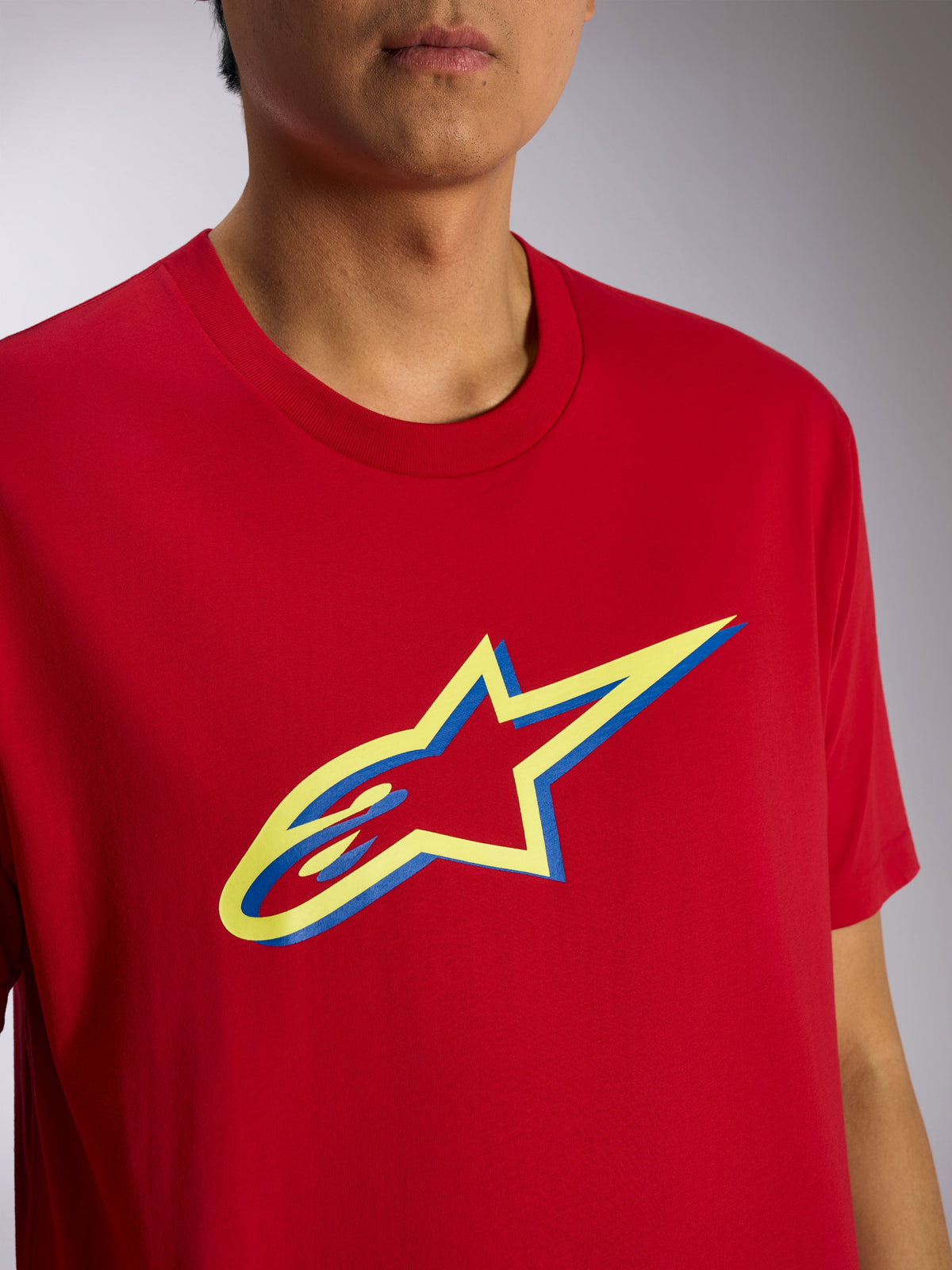 Alpinestars Ageless Shadow CSF Tee, t-shirt a maniche corte, rossa con grafica logo Ageless Shadow giallo e blu, vista ravvicinata su modello, streetwear casual motorsport