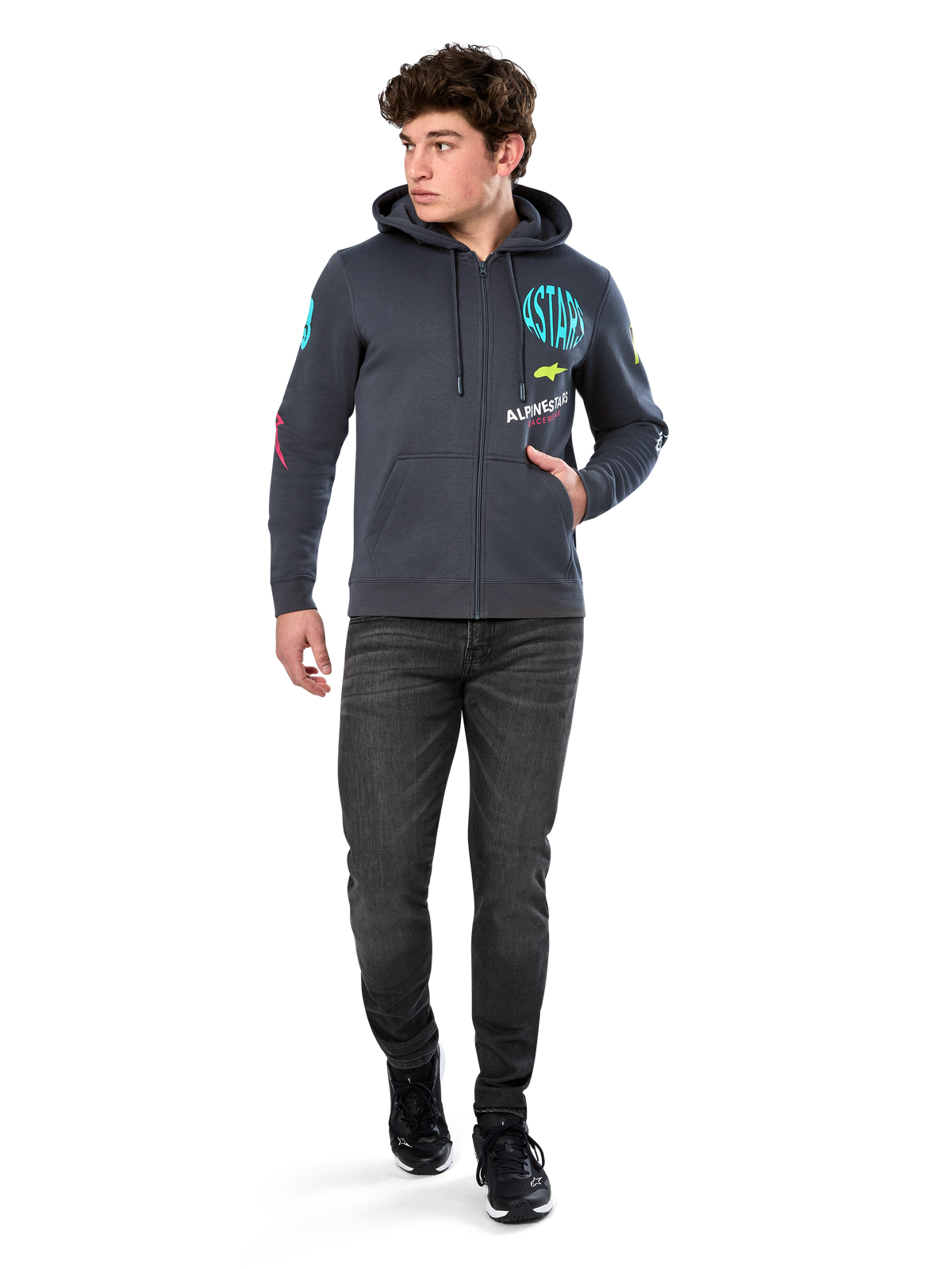 Alpinestars Variegate Hoodie, felpa in pile con zip frontale, grigio Gunmetal, indossata da un modello con jeans neri e sneakers, con marchio 'ASTARS' verde acqua e grafiche logo colorate su maniche e petto, streetwear casual ispirato al motorsport