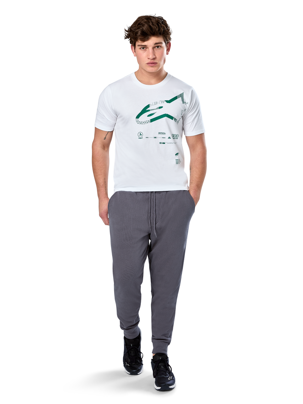 Alpinestars Geografica CSF Tee, maglietta a maniche corte, bianco, logo Astars verde con grafica multi-tech geografica, indossata con pantaloni sportivi grigi e sneakers nere, streetwear casual ispirato al motorsport
