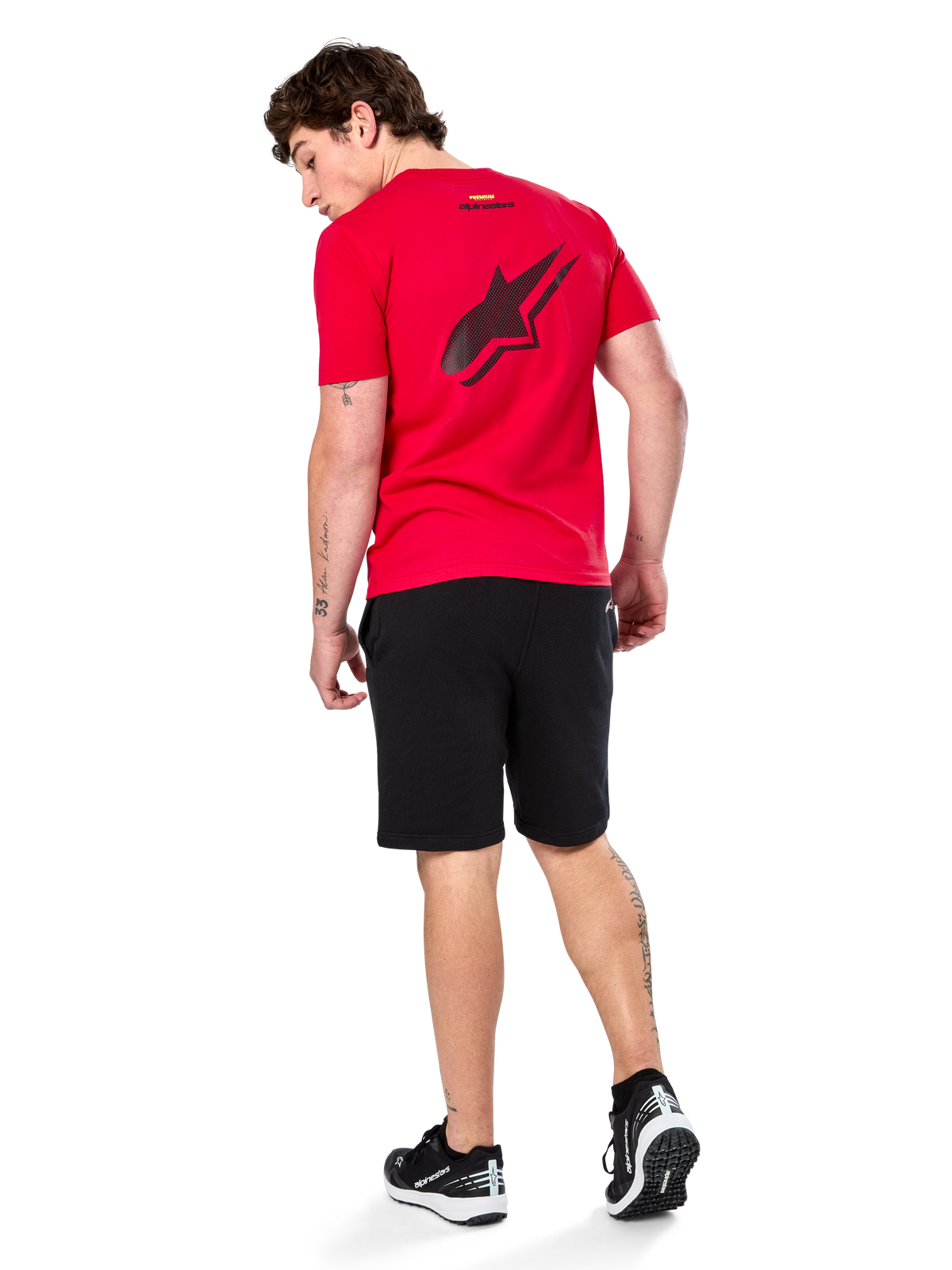 Alpinestars Formulate Csf Tee, maglietta a maniche corte, rosso, grande logo Astars traforato nero sul retro, indossata con pantaloncini neri e sneakers, streetwear casual ispirato al motorsport