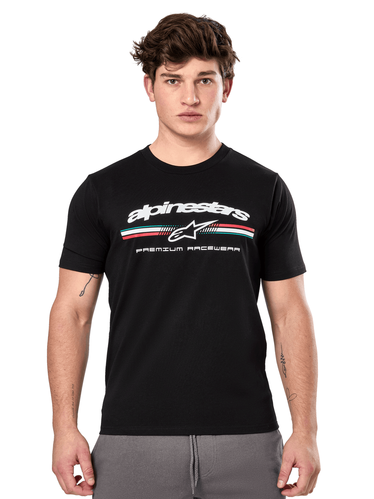 Alpinestars Prevail CSF Tee, maglietta nera a maniche corte indossata da un modello, con logo bianco, striscia tricolore e grafica "PREMIUM RACEWEAR", streetwear casual motorsport