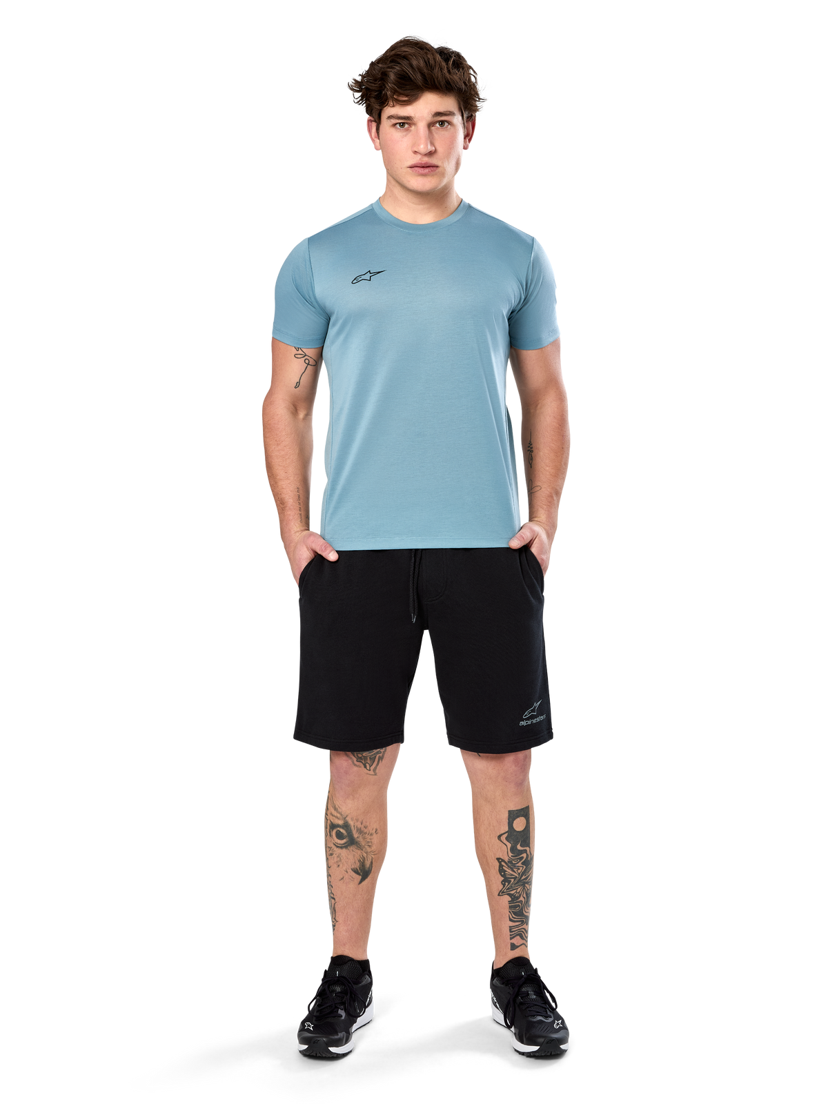 Alpinestars Point Performance Tee, t-shirt a maniche corte, blu ghiaccio, con un piccolo logo nero sul davanti, girocollo, indossata da un modello con pantaloncini neri e sneakers nere, abbigliamento sportivo casual traspirante