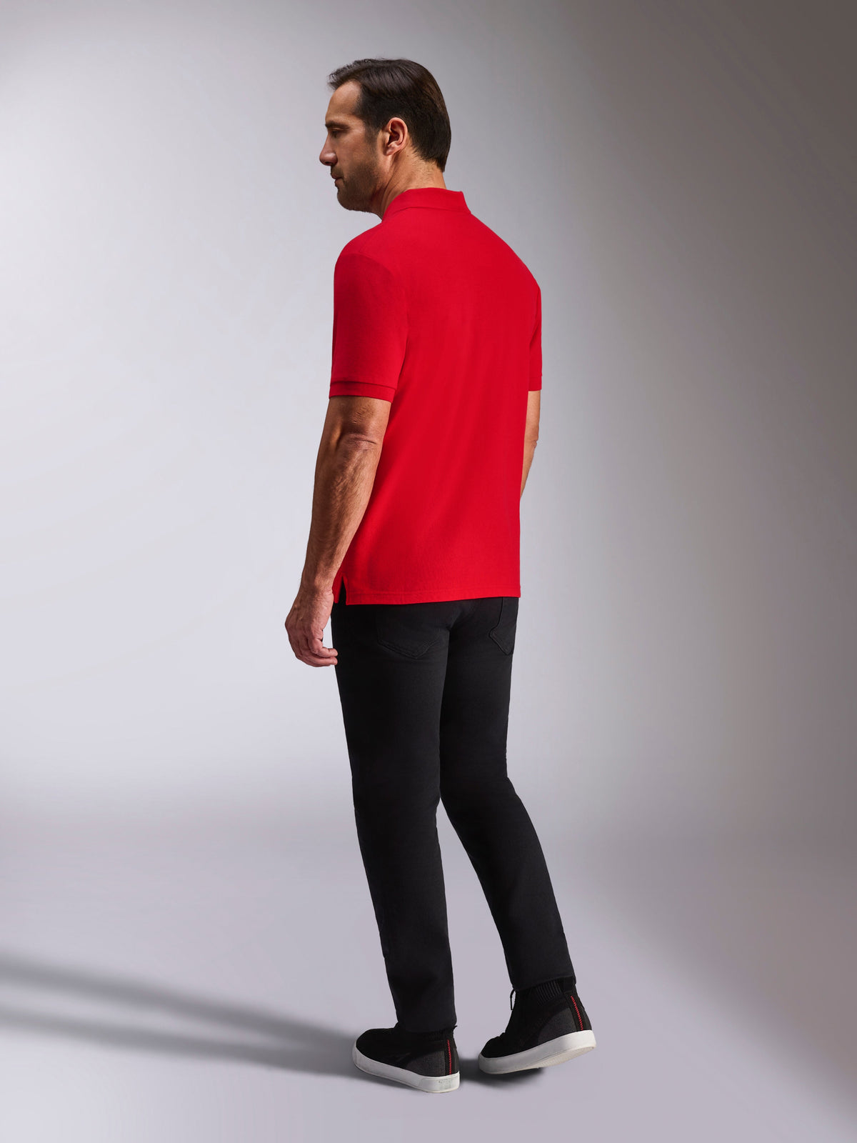 Alpinestars Polo Endeavor Classic, polo a maniche corte in piqué, rosso, vista posteriore e laterale, con colletto e polsini a coste, indossata con pantaloni e scarpe neri, streetwear casual ispirato al motorsport