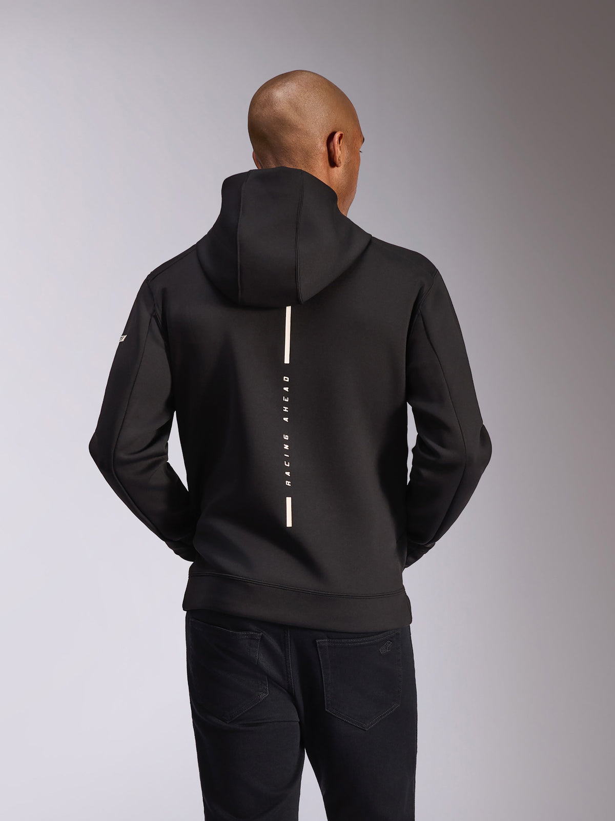 Felpa con cappuccio Alpinestars Insight, vista posteriore, nera, striscia bianca verticale con scritta 'RACING AHEAD', logo testuale sulla manica, streetwear casual ispirato al motorsport