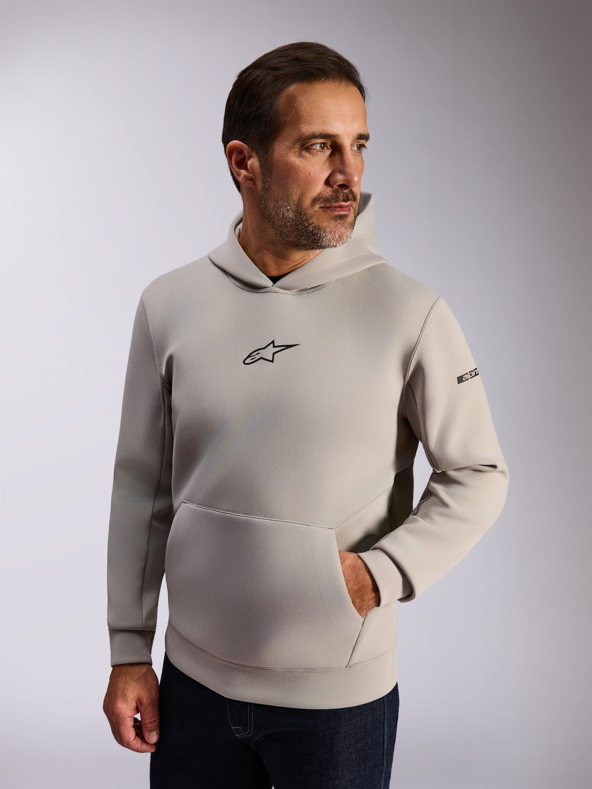 Alpinestars Insight Hoodie, streetwear casual lifestyle, pile grigio cemento, logo Astars nero frontale, tasca a marsupio, scritta sulla manica, cappuccio foderato in rete, abbigliamento moderno ispirato al motorsport