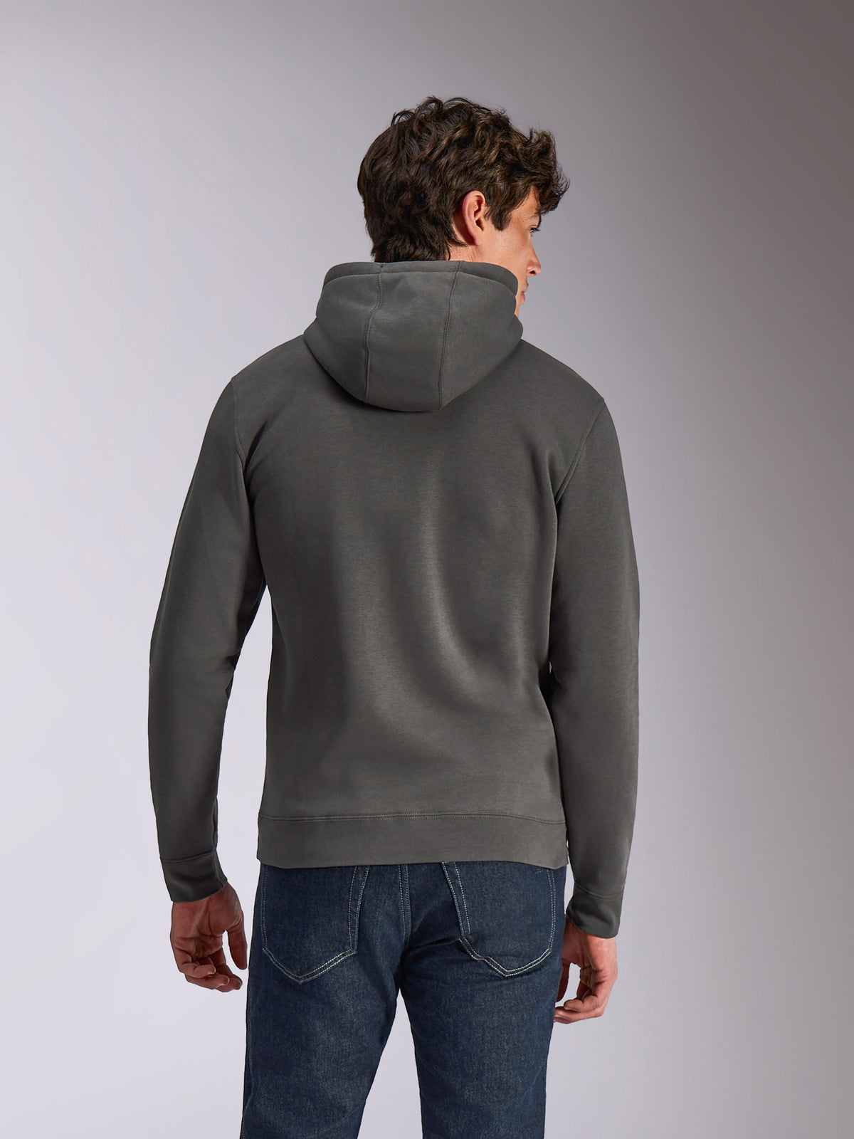 Alpinestars Ellipsoid Hoodie, felpa con cappuccio grigio gunmetal, abbigliamento sportivo casual, vista posteriore di un uomo che indossa una felpa in pile, orlo e polsini a coste, abbinata a jeans blu