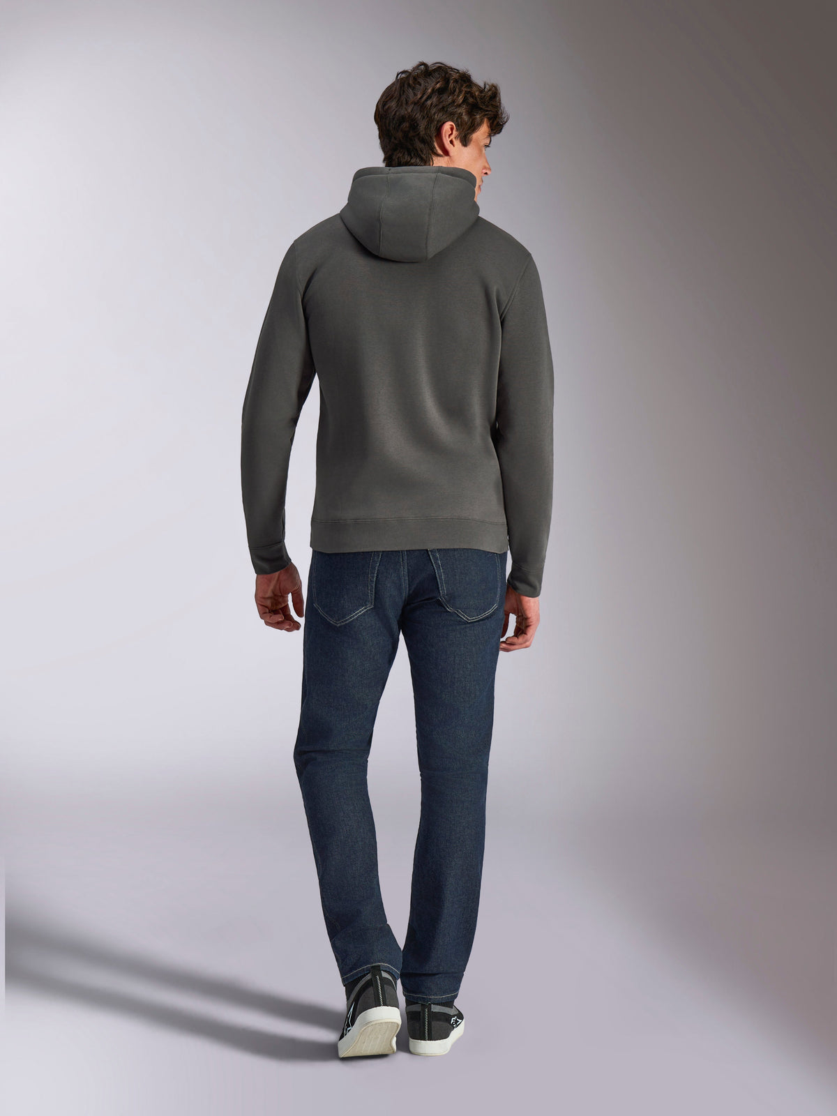 Alpinestars Ellipsoid Hoodie, felpa pullover con cappuccio color grigio gunmetal, vista posteriore, indossata da un modello con jeans in denim scuro e sneakers nere, streetwear casual ispirato al motorsport