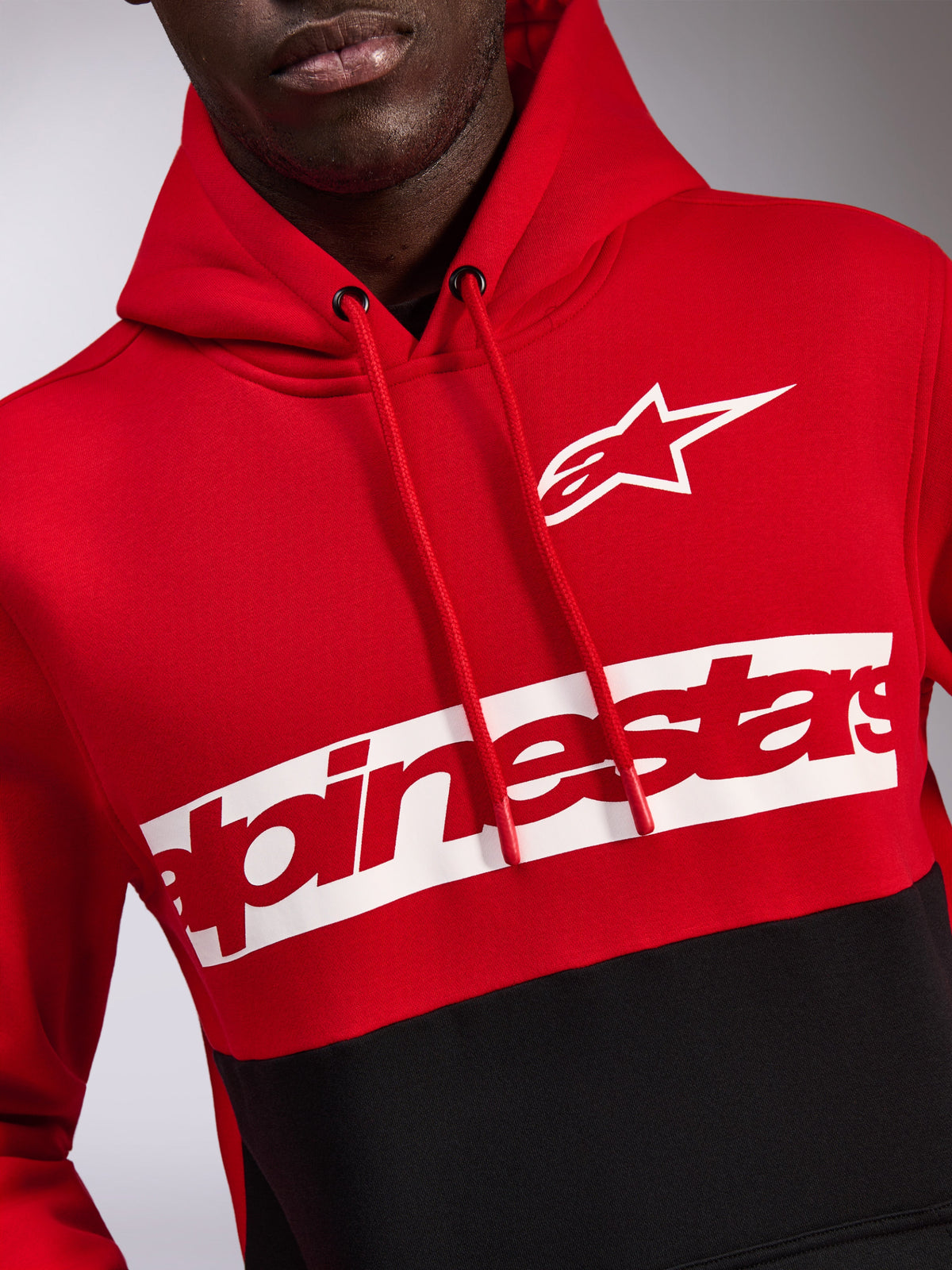 Felpa con cappuccio Alpinestars Parallel, pile con design a blocchi di colore rosso e nero, logo Astars bianco e scritta Alpinestars rossa su una banda bianca sul petto, cappuccio con cordino, streetwear casual ispirato al motorsport