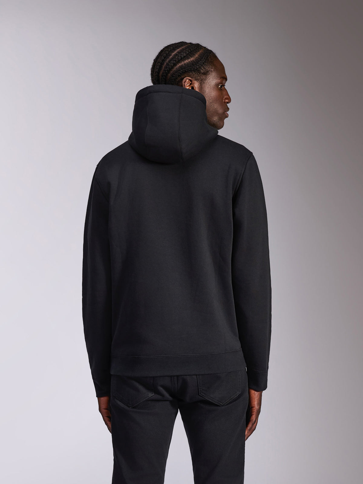 Alpinestars Pulse Hoodie, nera, vista posteriore su modello, streetwear casual, felpa in pile con cappuccio dal design nero a tinta unita, polsini e orlo a coste, abbinata a pantaloni neri.
