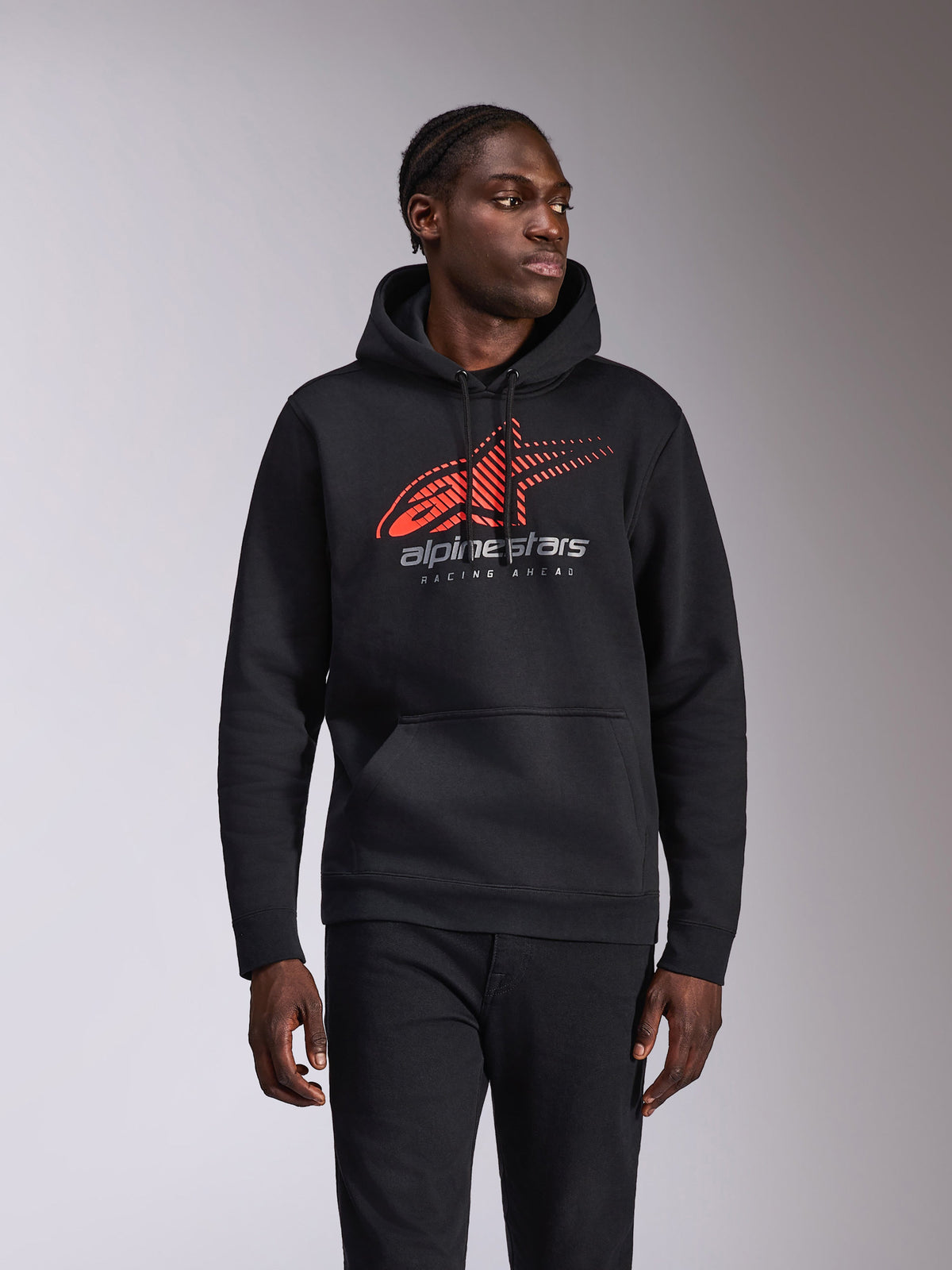 Alpinestars Pulse Hoodie, felpa casual con cappuccio, nera con logo Astars rosso e grigio caratterizzato da sfumatura speed line e testo 'Racing Ahead', cappuccio con cordino e tasca a marsupio, abbigliamento streetwear ispirato al motorsport indossata da un modello