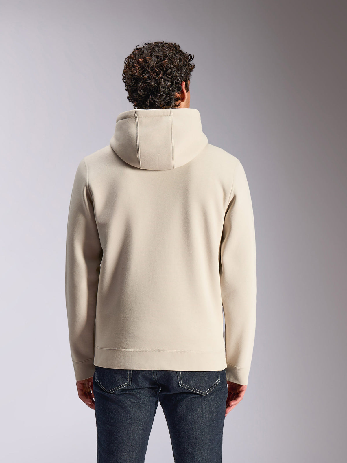 Felpa con cappuccio Alpinestars Pulse, color sabbia, vista posteriore di un modello maschile che indossa il pullover a tinta unita con cappuccio, abbinato a jeans in denim scuro, streetwear casual ispirato al motorsport