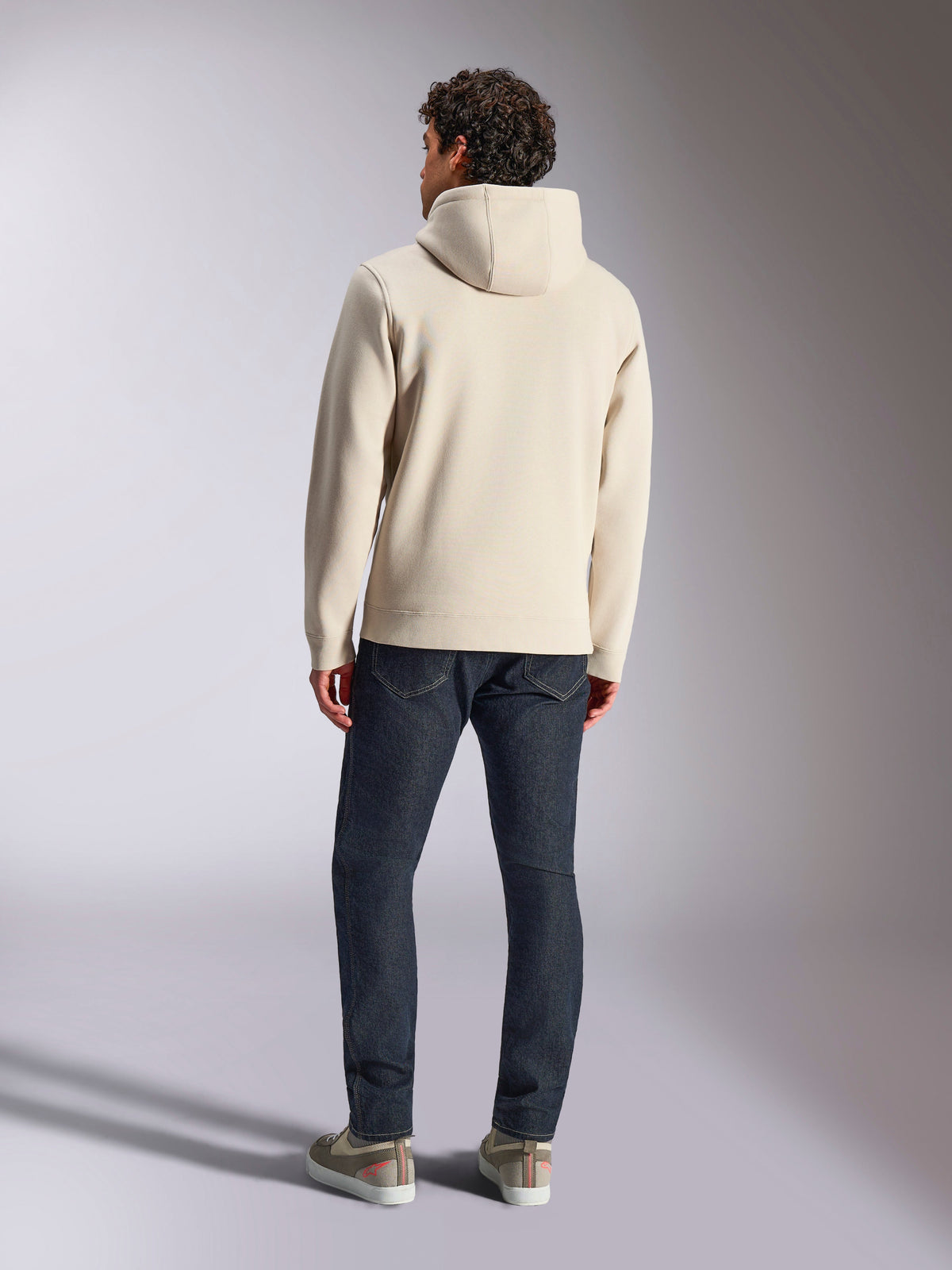 Alpinestars Pulse Hoodie, Off White, vista posteriore di un uomo che indossa una felpa casual in pile con cappuccio, jeans scuri e sneakers, design moderno sportswear