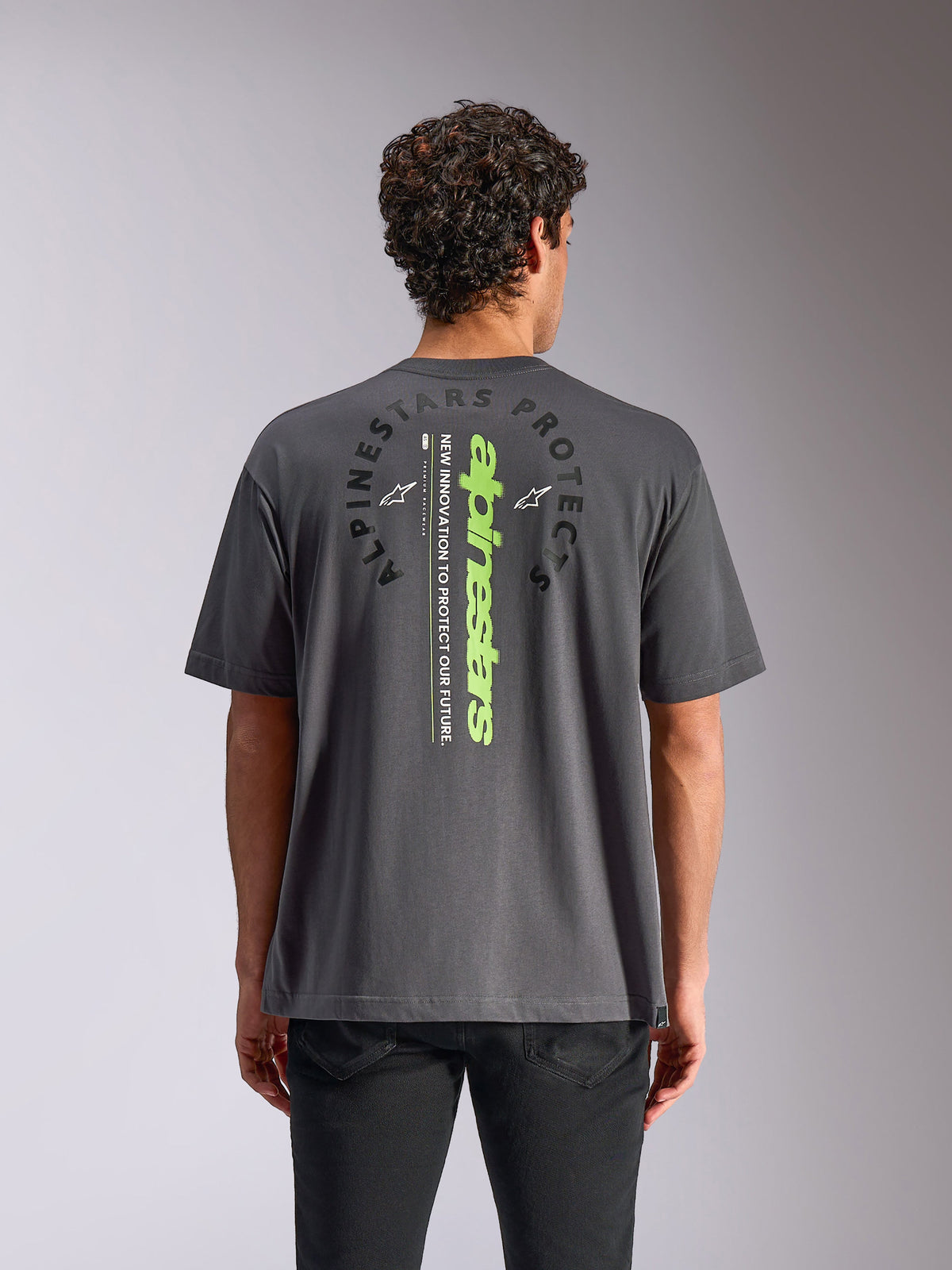 Alpinestars Overhang Oversized CSF Tee, t-shirt a maniche corte, grigio antracite, vista posteriore con marchio verticale verde neon e grafica circolare, vestibilità rilassata oversize, streetwear casual ispirato al motorsport