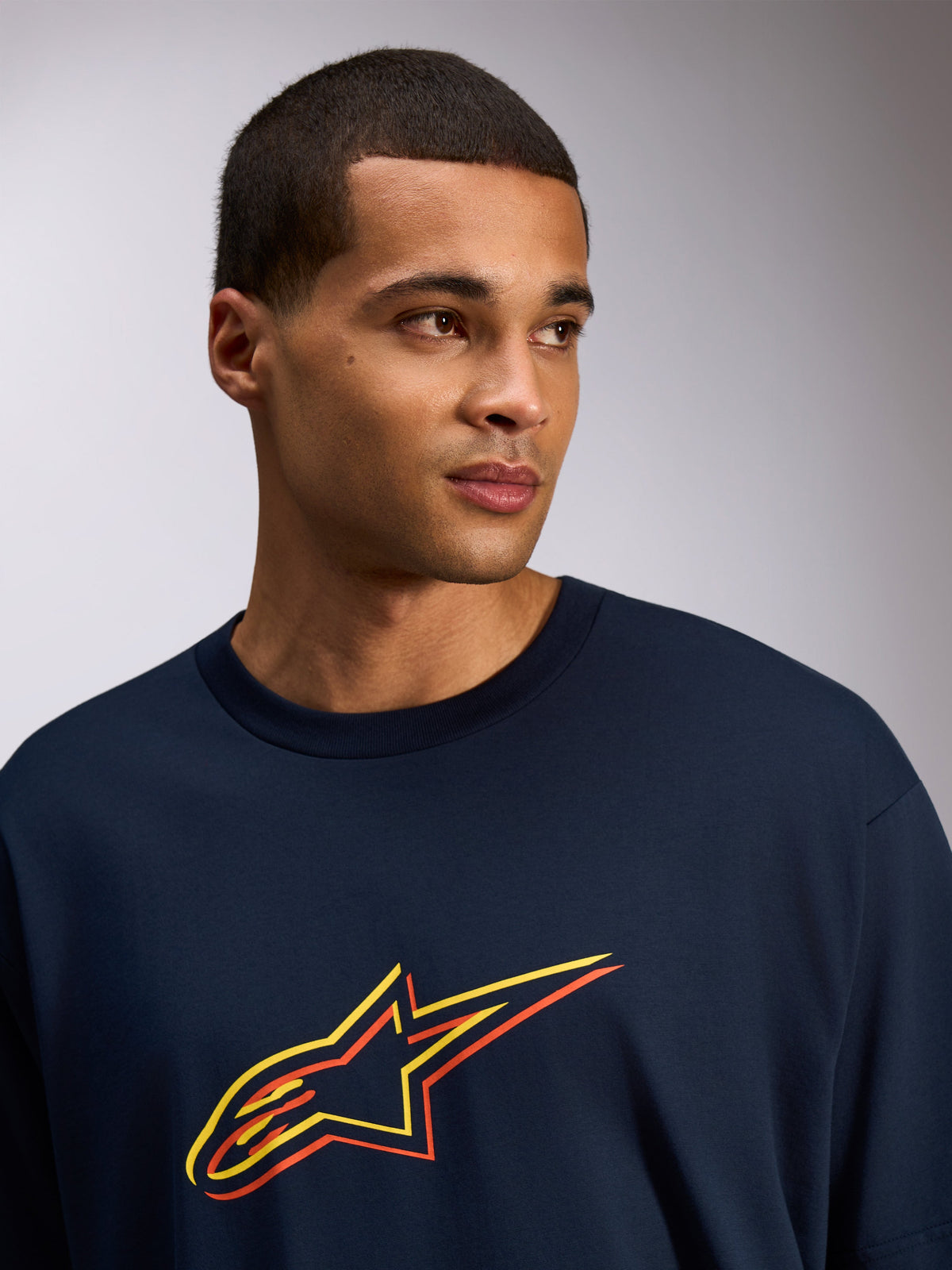 Alpinestars Alter Oversized CSF Tee, maglietta a maniche corte, blu navy, logo Astars con stampa sfalsata gialla e arancione, stile streetwear casual indossata da un modello