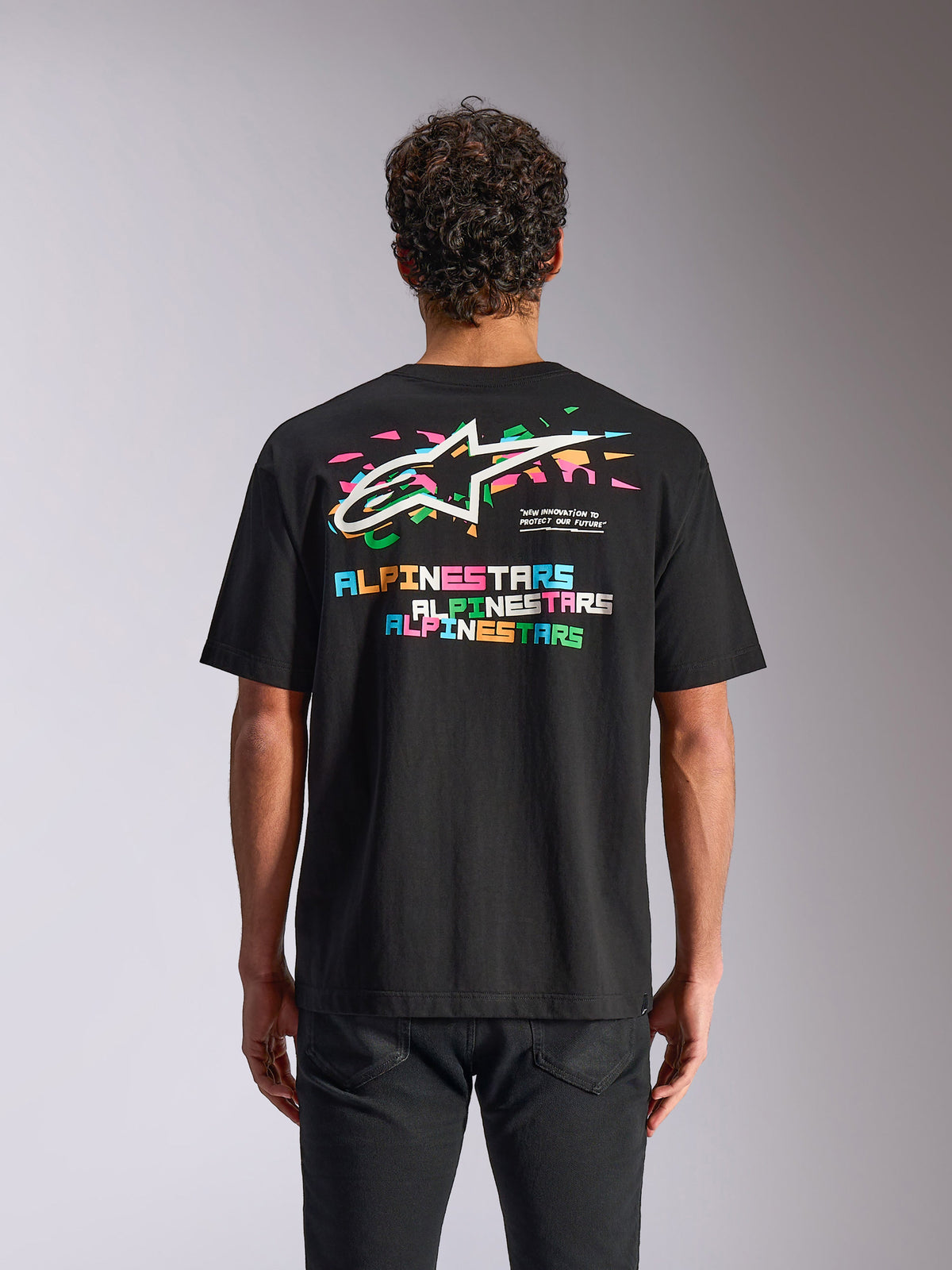 Alpinestars Wild Oversized CSF Tee, maglietta a maniche corte, nero, vista posteriore che mostra il vivace logo Astars multicolore ed elementi grafici, streetwear casual da motorsport