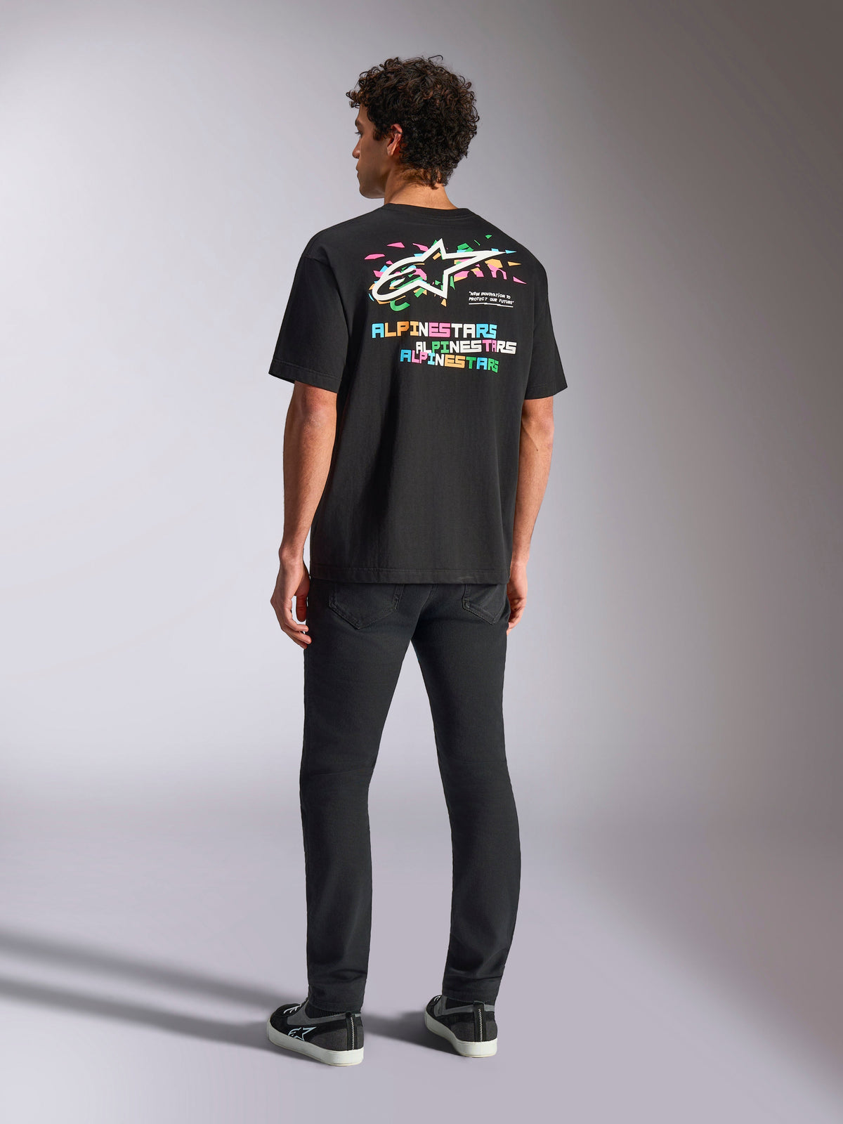 T-shirt Alpinestars Wild Oversized CSF, maglia a maniche corte, nero, caratterizzata da una grande grafica multicolore sul retro con logo Astars e scritte colorate, vestibilità oversize, indossata con pantaloni neri slim-fit per un look casual streetwear
