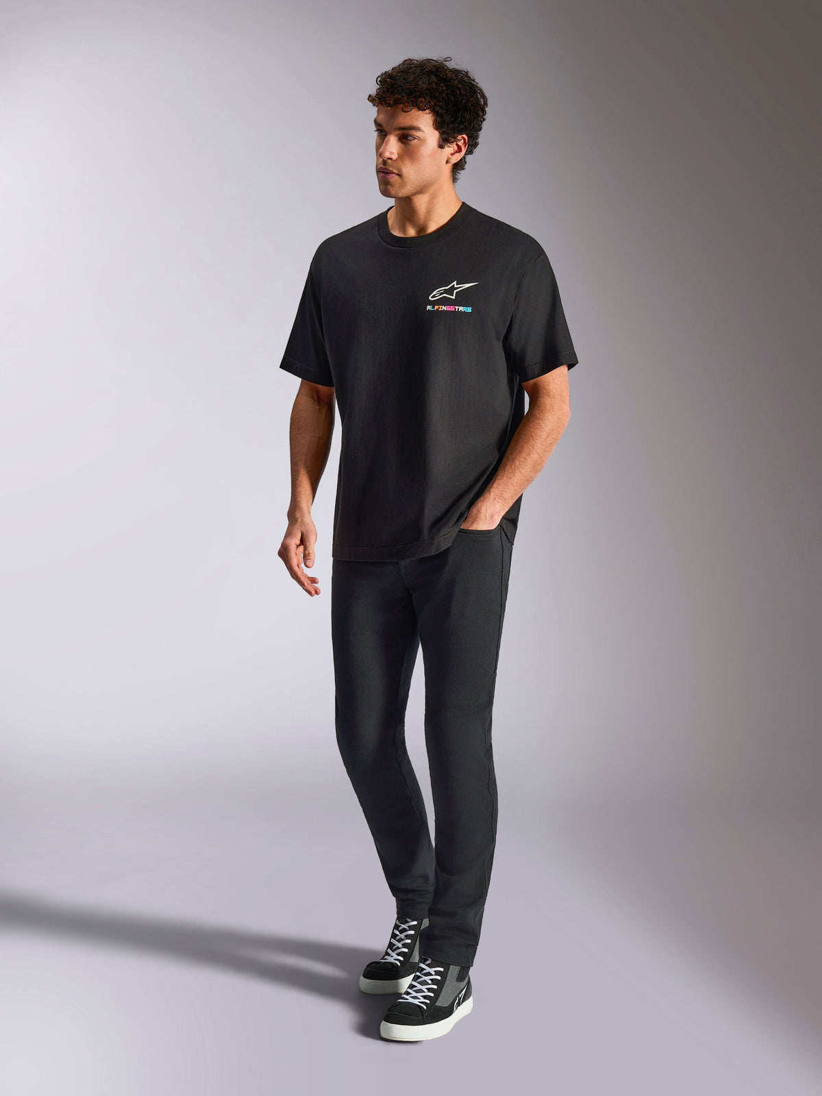 Alpinestars Wild Oversized CSF Tee, t-shirt a maniche corte, nero, logo Astars multicolore sul petto, stile casual streetwear indossata da un modello con pantaloni neri e sneakers alte