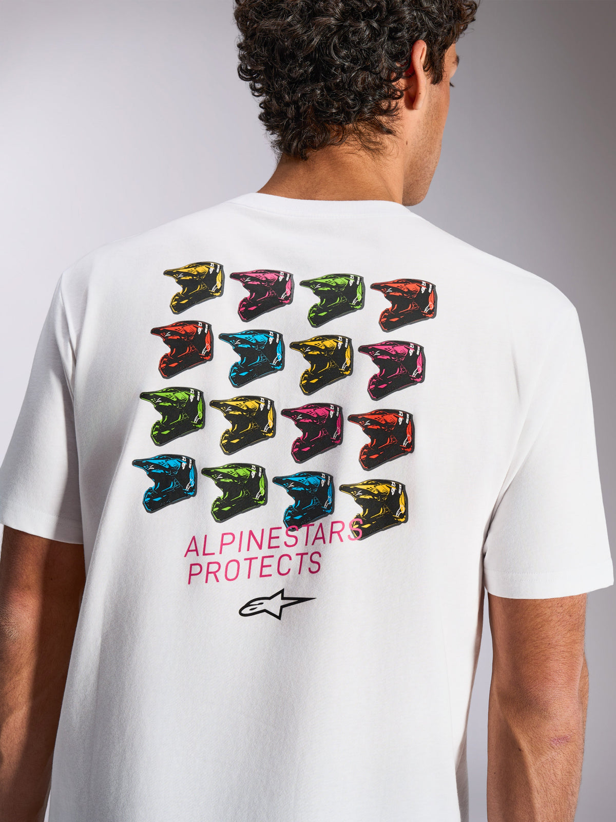 Maglietta Alpinestars Pop Helmet CSF, t-shirt a maniche corte, bianco, grafica sul retro con griglia colorata di caschi M10, testo 'ALPINESTARS PROTECTS' e logo Astars, abbigliamento sportivo casual motorsport