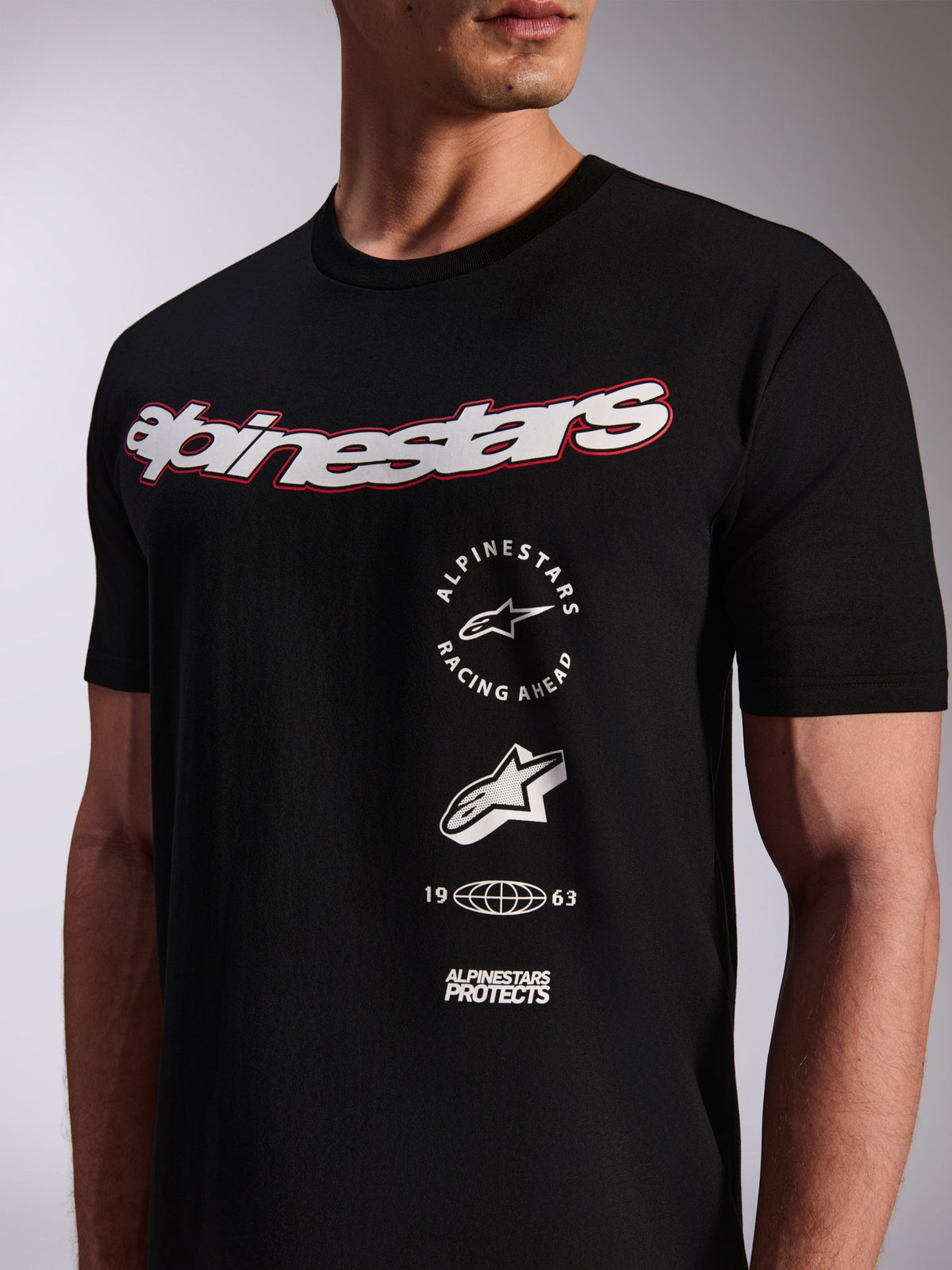 Alpinestars Abus CSF Tee, t-shirt a maniche corte, nera, grande logo bianco sul petto con profilo rosso, loghi grafici verticali multipli impilati, abbigliamento casual motorsport streetwear
