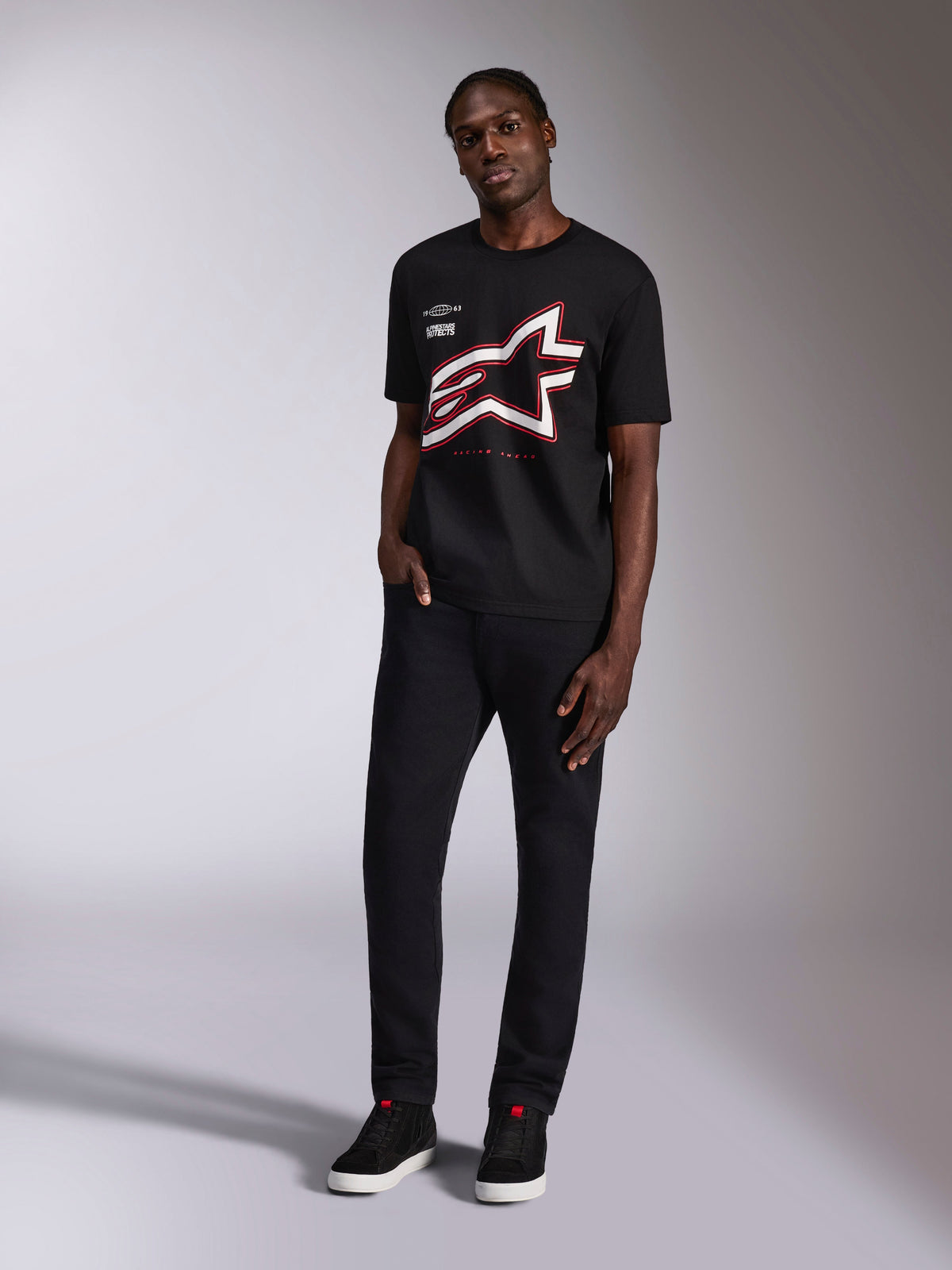 Alpinestars Authority CSF Tee, t-shirt a maniche corte, nero, grande logo Astars ritagliato con contorni rossi e bianchi, indossata da un modello, abbigliamento casual motorsport streetwear