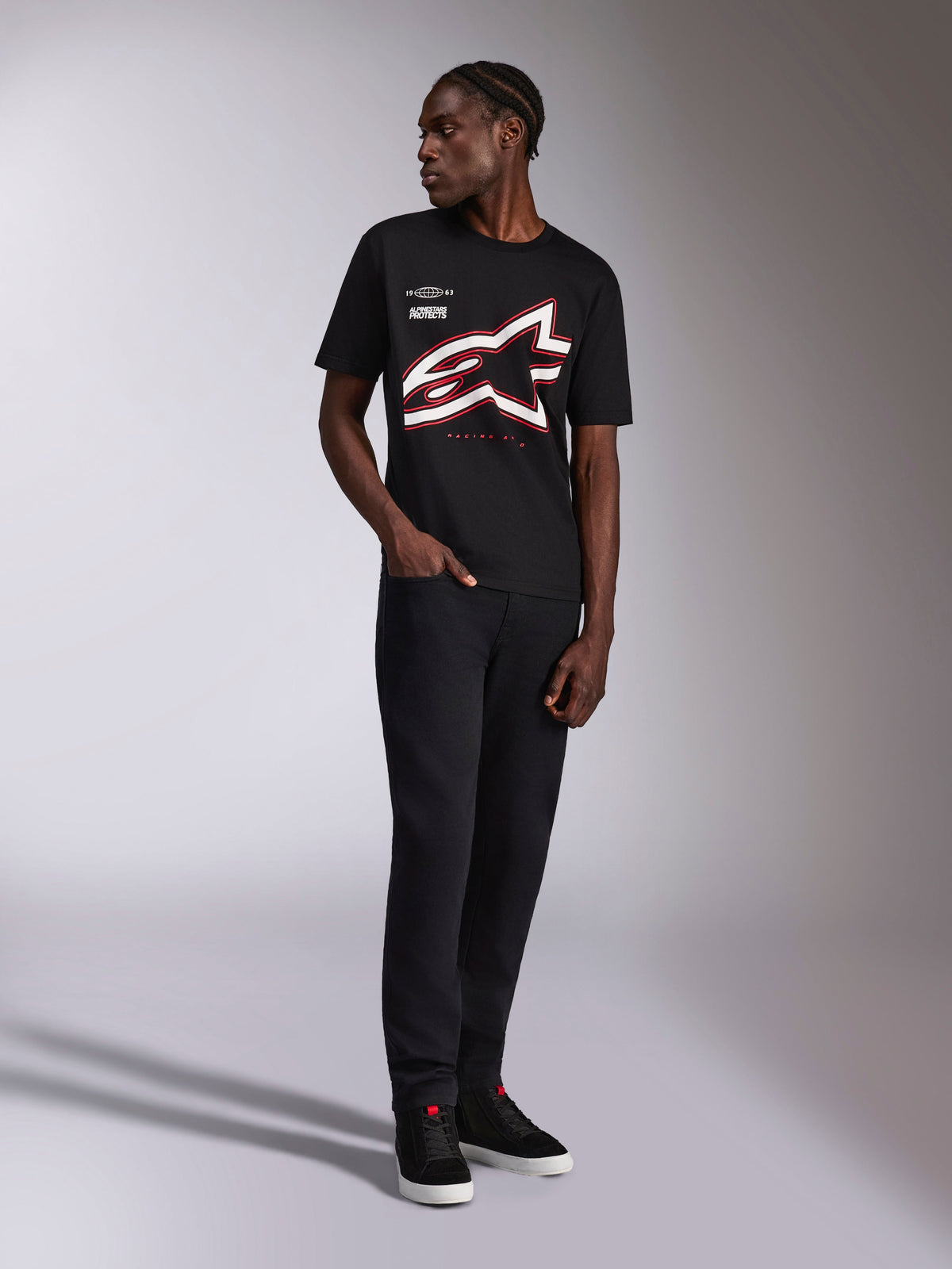 Alpinestars Authority CSF Tee, t-shirt a maniche corte, nero, grande logo Astars profilato rosso e bianco ritagliato, indossata da un modello con pantaloni e sneakers neri, streetwear motorsport casual