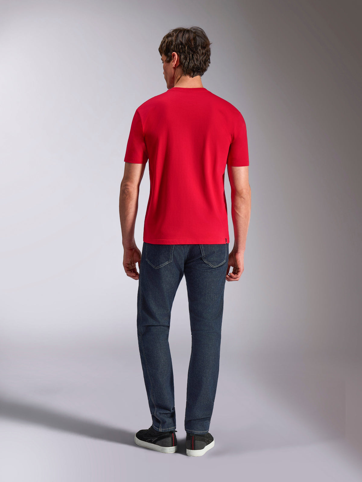 Alpinestars Authority CSF Tee, t-shirt a maniche corte, rossa, vista posteriore su un modello che indossa jeans blu scuro e sneakers nere, streetwear casual ispirato al motorsport
