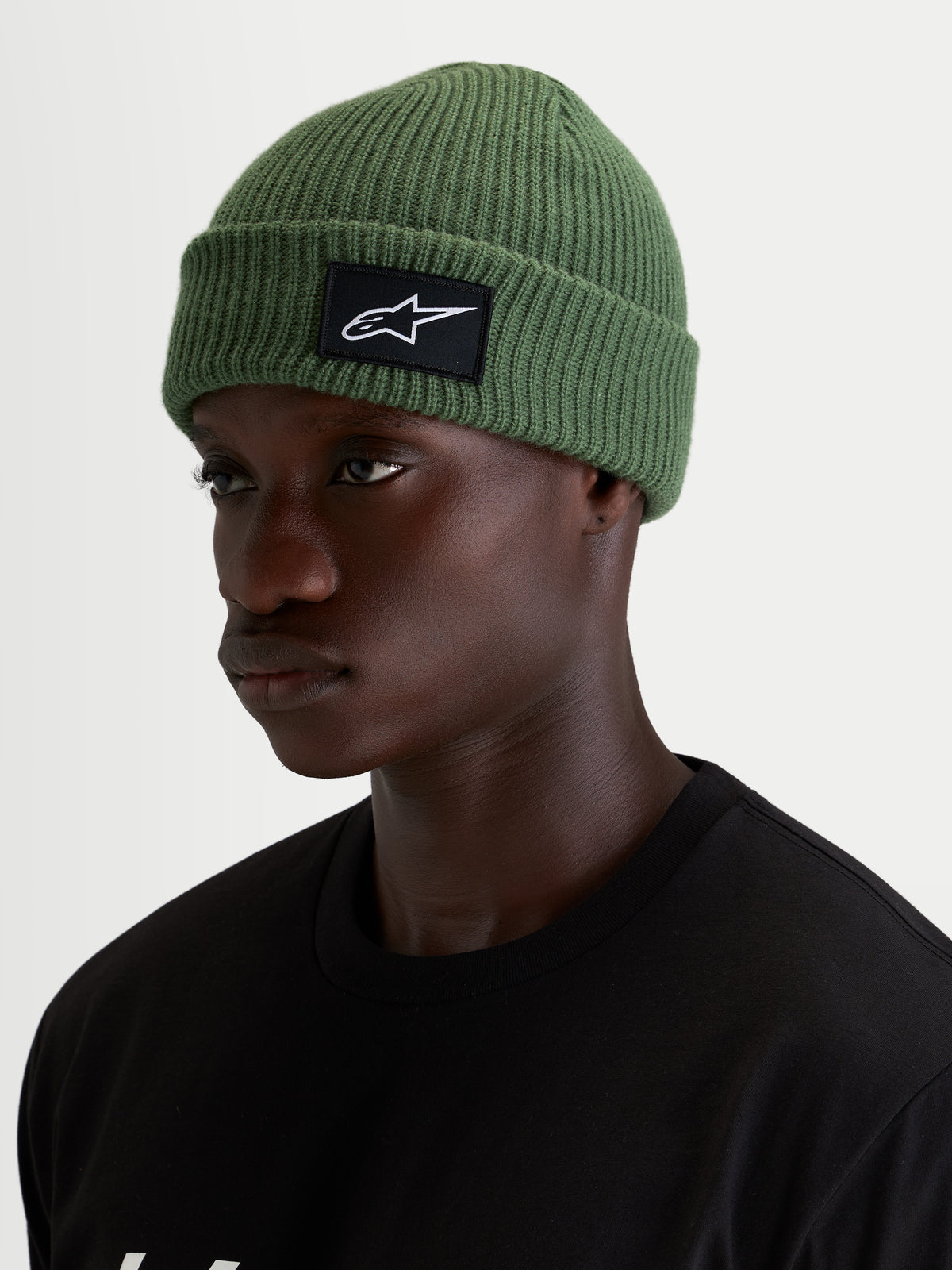 Berretto Alpinestars Unload Rib Cuff, berretto sportswear verde pisello, indossato da un modello, con struttura a maglia a coste e patch frontale SAstars nera e bianca