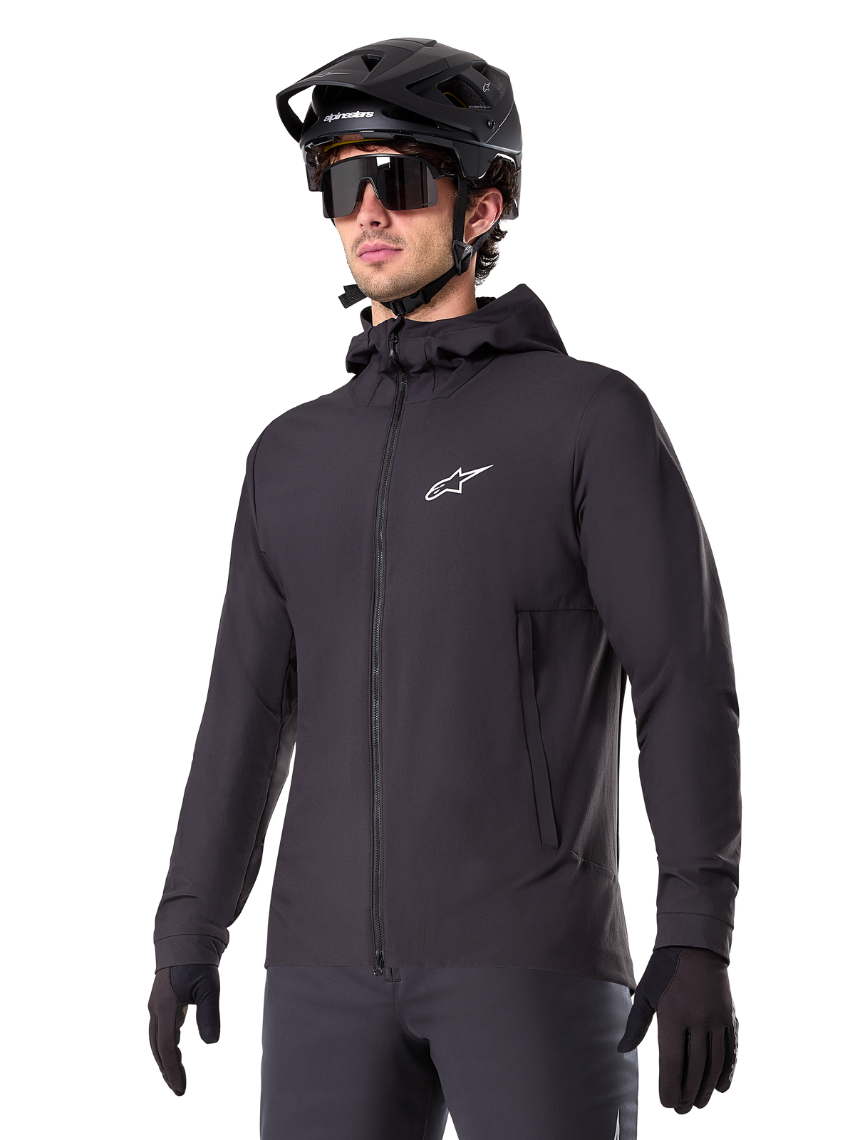 Alpinestars A-Dura Thermal Jacket, giacca da ciclismo nera, design con cappuccio e zip frontale, logo a stella bianco sul petto, indossata con casco da mountain bike e guanti neri, abbigliamento sportivo per il trail riding in climi freddi