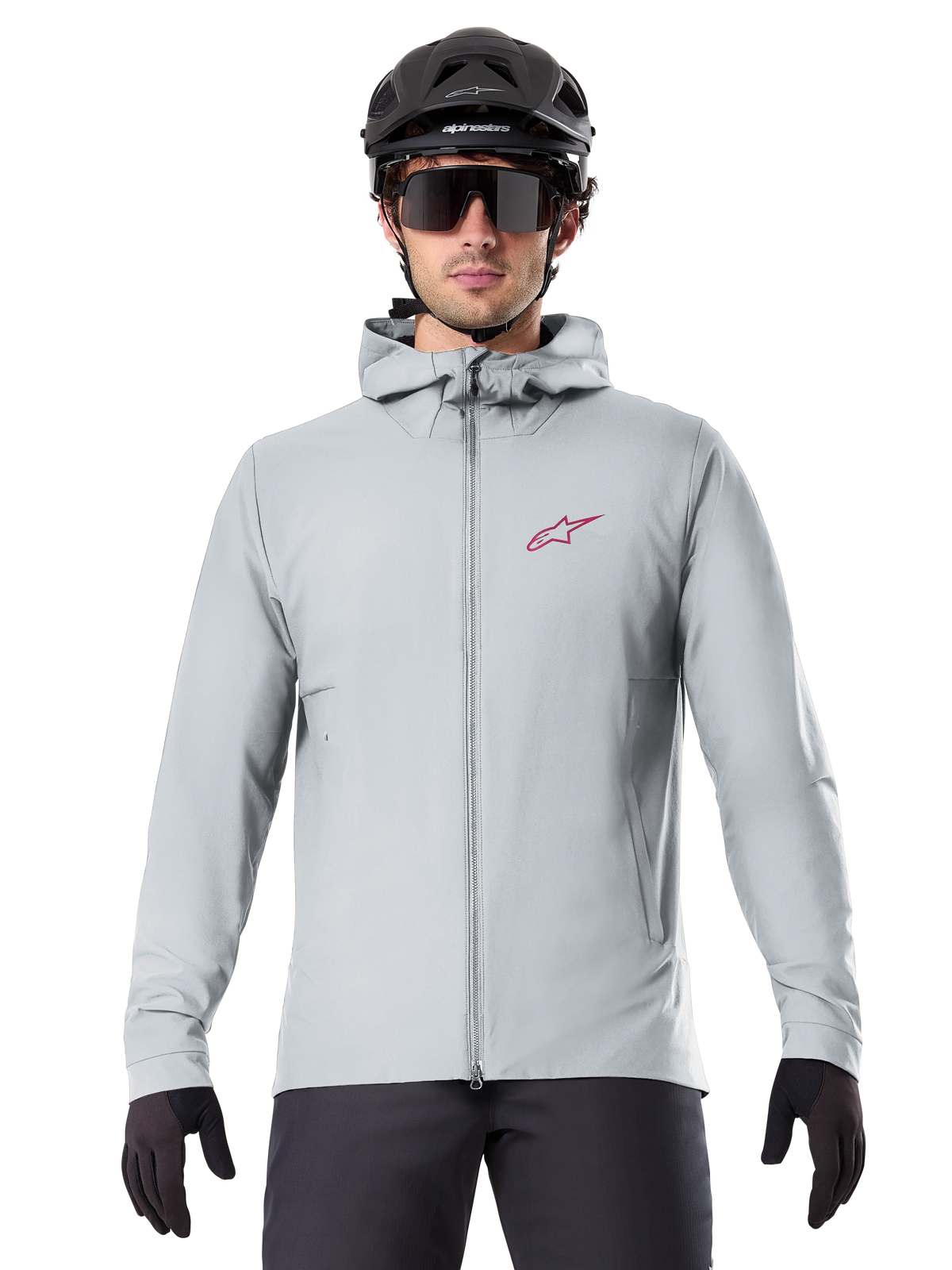 Alpinestars A-Dura Thermal Jacket in Titanium, giacca da ciclismo grigio chiaro con cappuccio e logo a stella rosso sul petto, indossata da un rider con casco da MTB nero, occhiali da sole e guanti, abbigliamento isolante per mountain bike