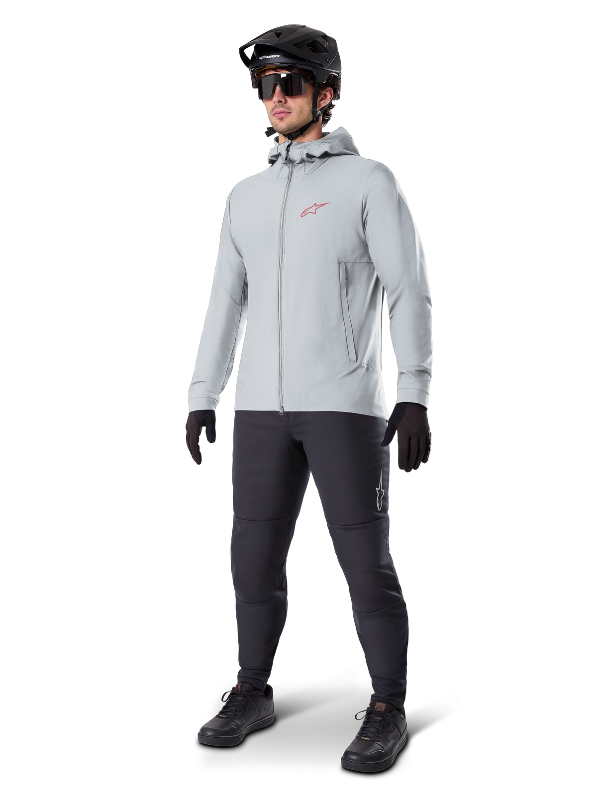 Giacca termica Alpinestars A-Dura in Titanium, giacca da ciclismo grigio chiaro con cappuccio e logo Alpinestars rosso sul petto, indossata da un uomo con casco da MTB nero, occhiali da sole, pantaloni grigio scuro e guanti neri, attrezzatura professionale da mountain bike
