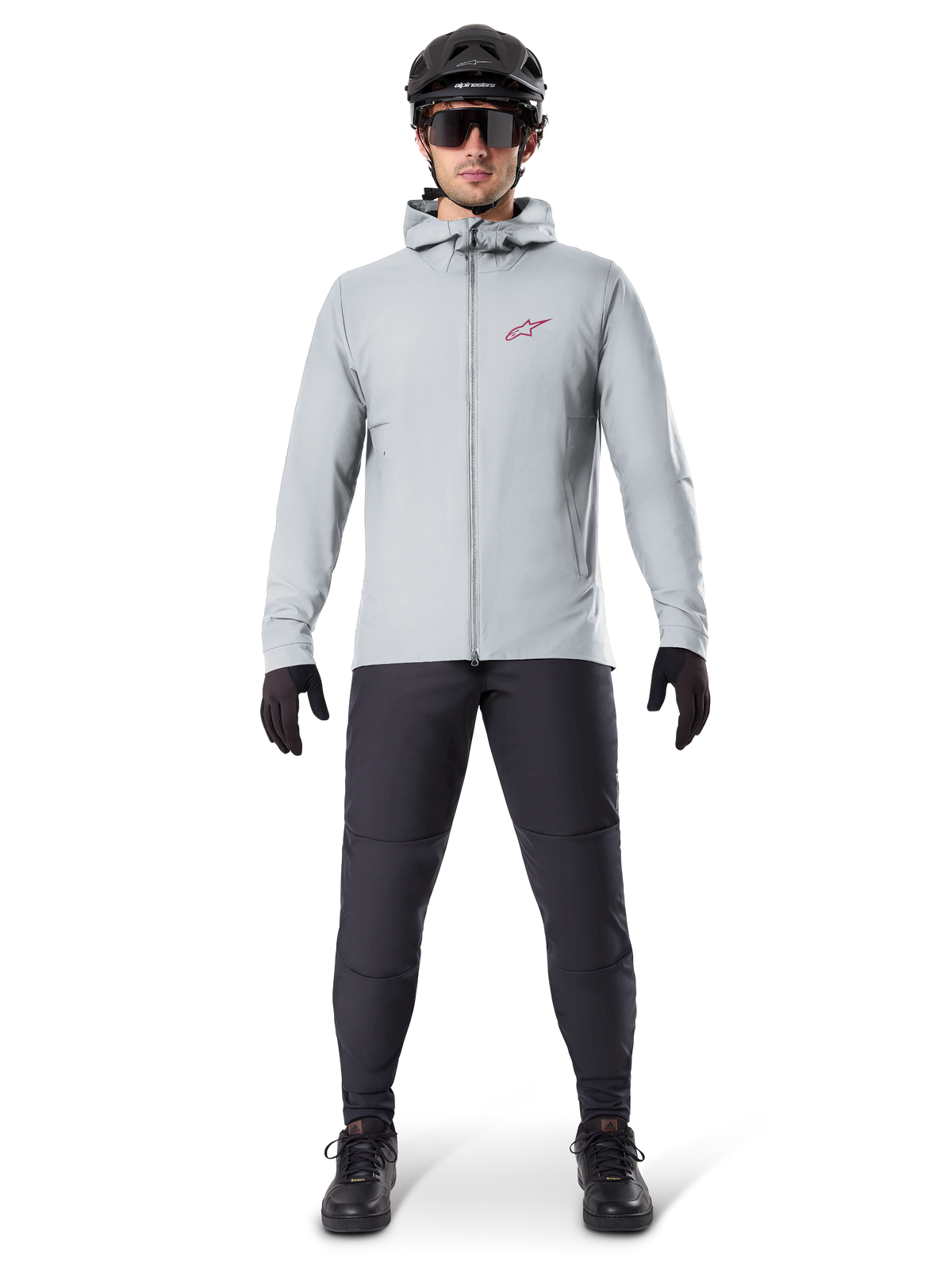 Giacca Termica Alpinestars A-Dura, grigio titanio, giacca da ciclismo indossata con pantaloni da mountain bike neri, guanti e casco, caratterizzata da un piccolo logo a stella rosso sul petto e cerniera frontale completa, abbigliamento isolante leggero per la guida fuoristrada