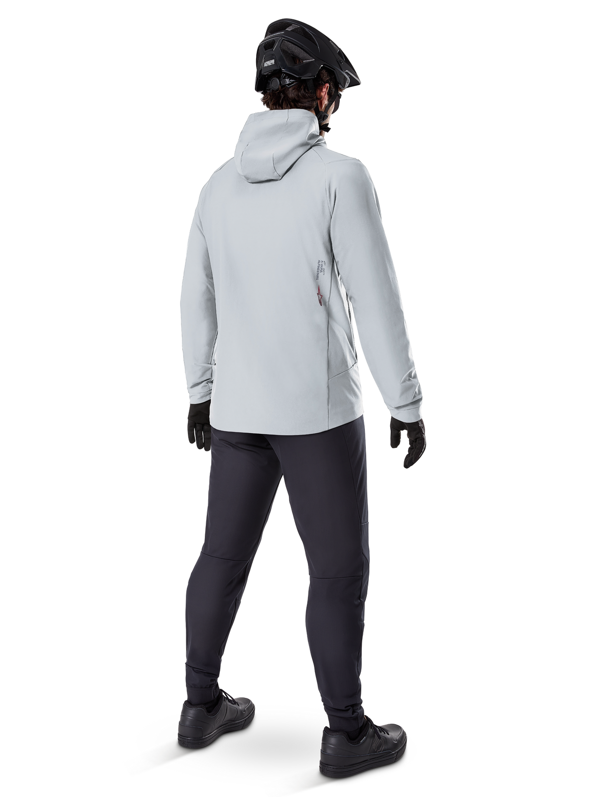 Giacca termica Alpinestars A-Dura in Titanium, vista posteriore di un ciclista che indossa una giacca termica grigio chiaro con cappuccio, abbinata a casco da MTB nero, guanti neri e pantaloni grigio scuro, abbigliamento tecnico per mountain bike