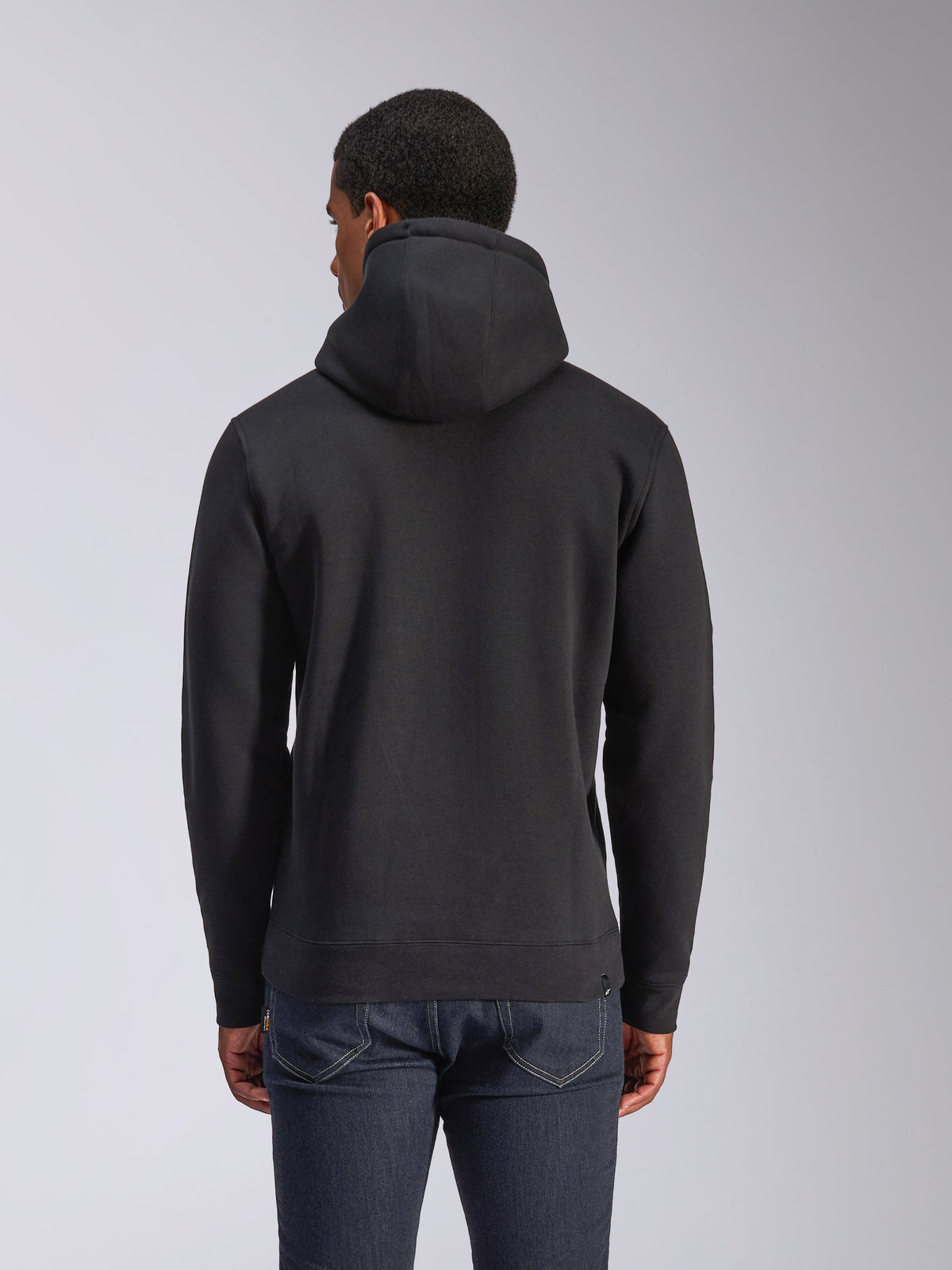 Alpinestars Blaze V3 Hoodie, vista posteriore di una felpa in pile nera a pullover, casual streetwear, con polsini e orlo a coste, cappuccio foderato in jersey, indossata con jeans blu scuro