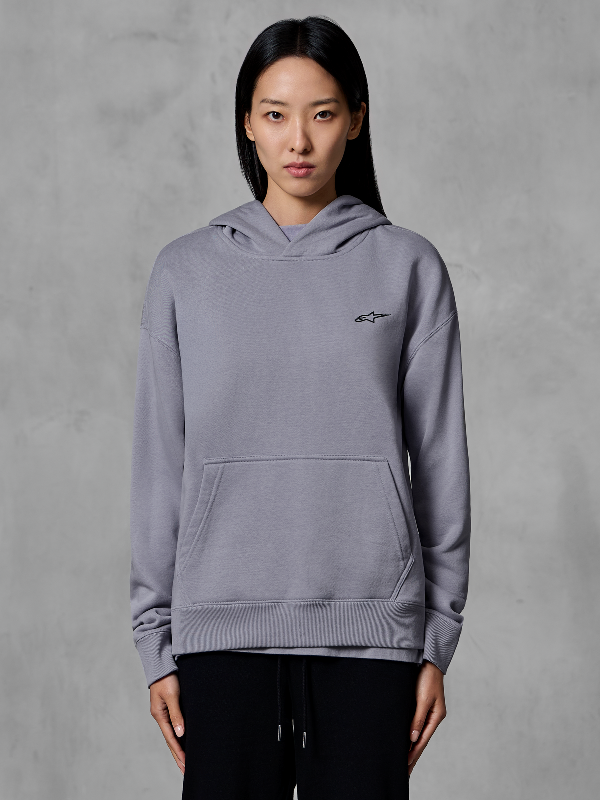 Felpa con cappuccio Alpinestars Essentials Ageless, abbigliamento sportivo casual, argento con piccolo logo nero, tasca a marsupio, pullover con cappuccio, indossata da una modella, abbigliamento lifestyle moderno