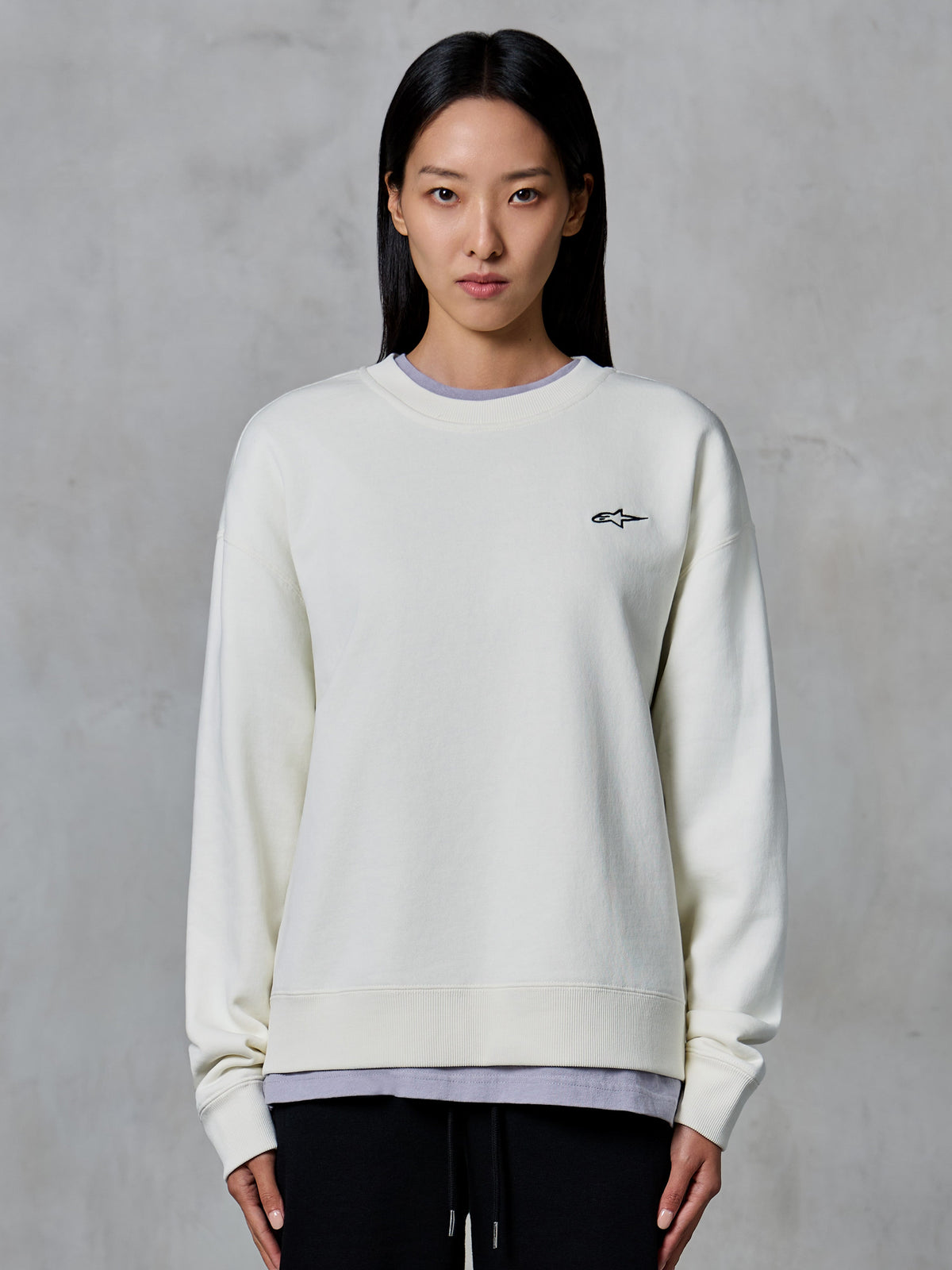 Alpinestars Essentials Ageless Crew, felpa girocollo, Off White, con un piccolo logo Alpinestars nero sul petto, abbigliamento lifestyle casual indossato da una donna