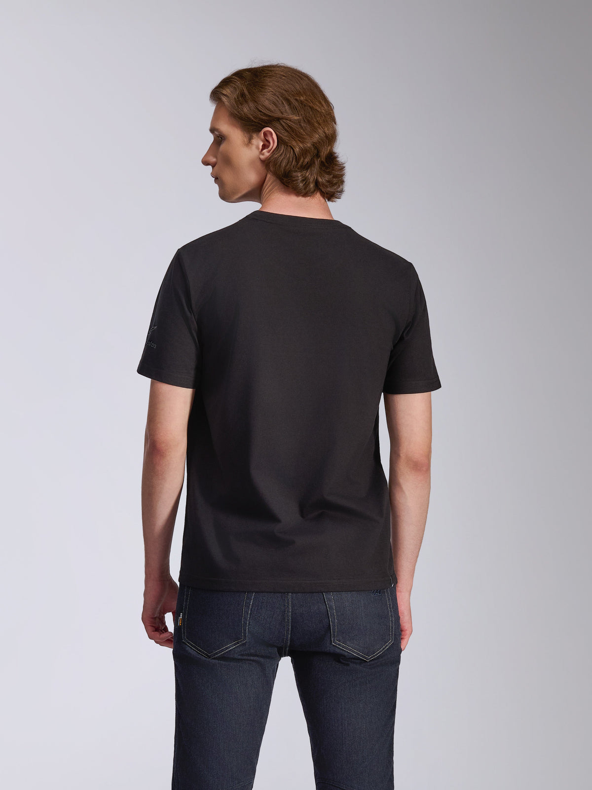 Alpinestars Global CSF Tee, maglietta a maniche corte, nero, vista posteriore indossata da un modello, abbinata a jeans blu scuro, streetwear casual motorsport
