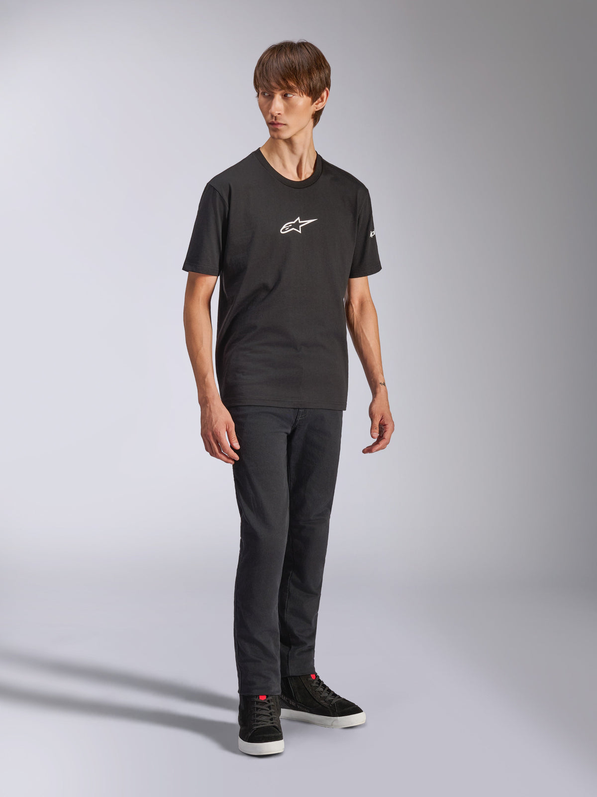 Alpinestars Frontal CSF Tee, t-shirt a maniche corte, nera, logo Astars bianco sul petto, indossata da un modello con jeans scuri e sneakers nere, streetwear casual performante