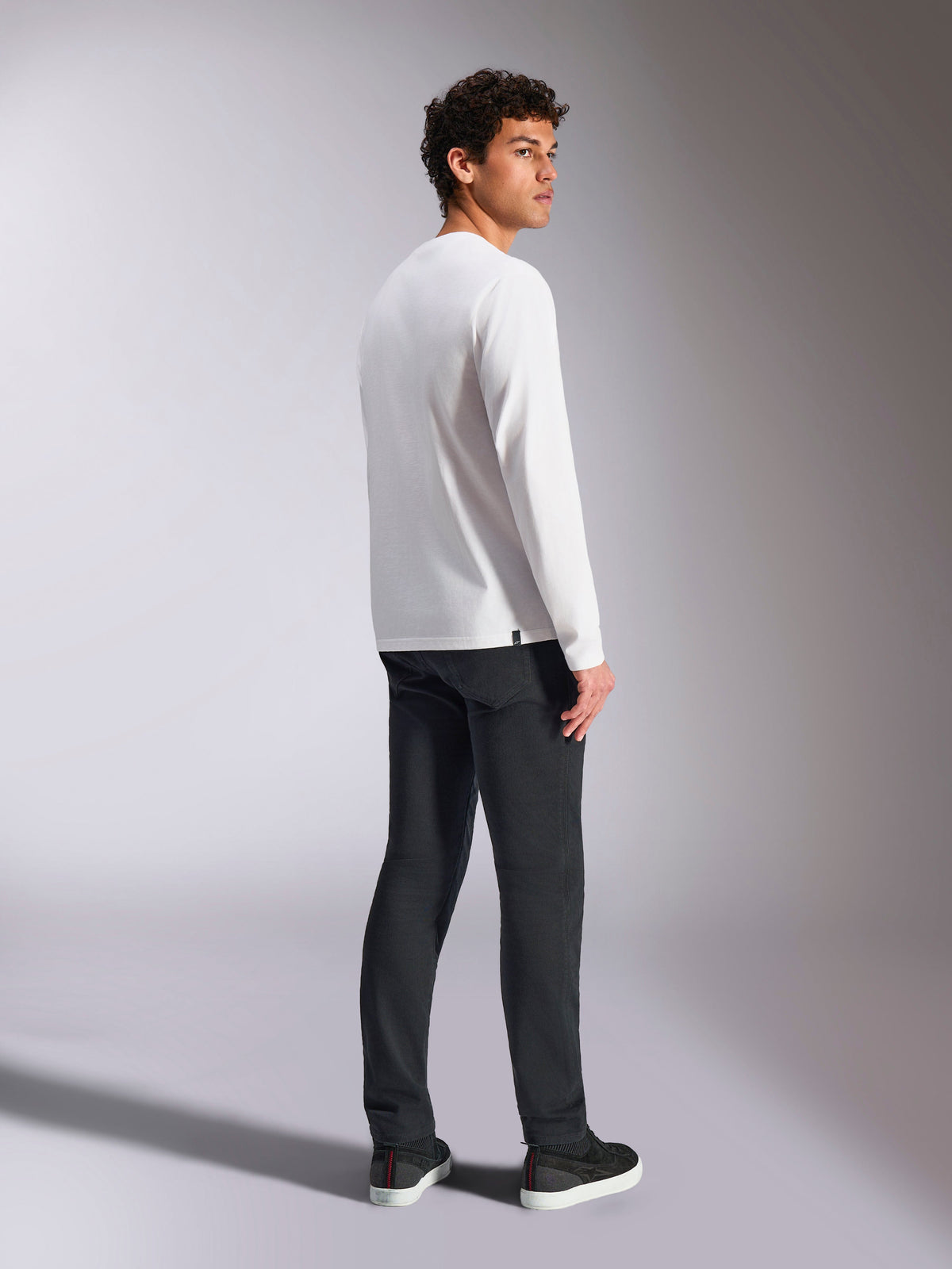 Alpinestars Trackside CSF Tee, maglietta a maniche lunghe, bianca, modello maschile visto di spalle con pantaloni neri, abbigliamento casual streetwear ispirato al motorsport