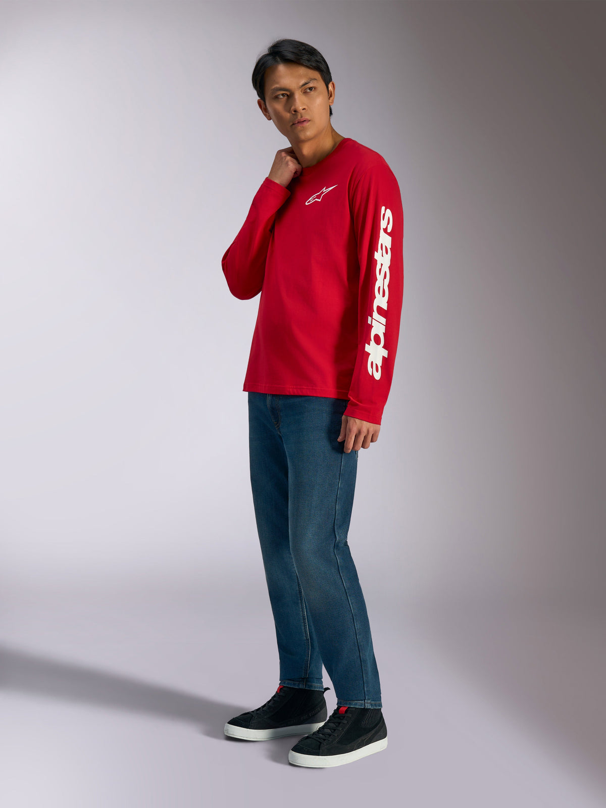 Alpinestars Trackside CSF Long Sleeve Tee, rossa con logo Alpinestars bianco su petto e manica, indossata da un modello con jeans blu e sneakers nere, streetwear casual ispirato al motorsport