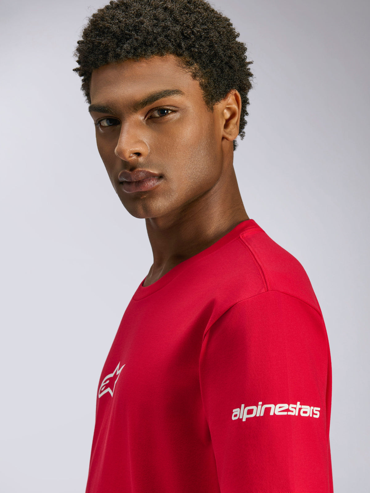 Alpinestars Frontal CSF Tee, t-shirt a maniche corte rossa, con loghi bianchi sul petto e sulla manica, indossata da un modello, streetwear casual performance motorsport