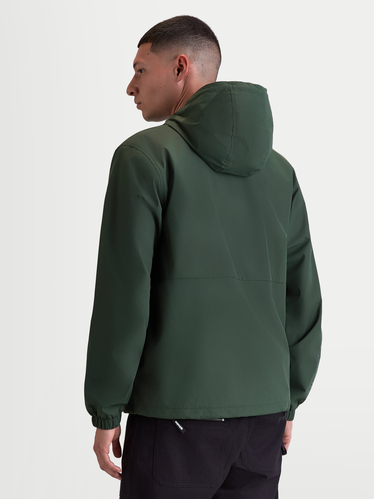 Alpinestars Giacca frangivento Speeder Resolve, giacca sportswear leggera con cappuccio per uso urbano, verde, in poliestere antivento con fodera in rete, vista posteriore su modello che mostra il design pulito della schiena e i polsini elastici.