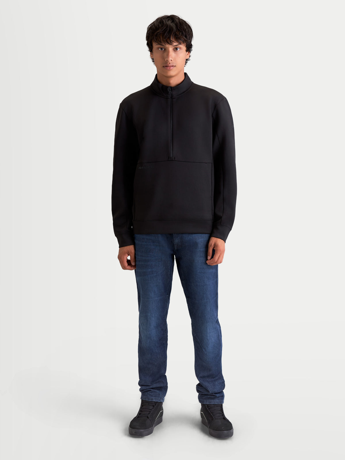 Alpinestars Felpa Apera Half-Zip, pullover sportswear da uomo con chiusura a mezza zip e tasca a marsupio, nero, branding tonale e stile ispirato al motorsport, indossata da un modello.