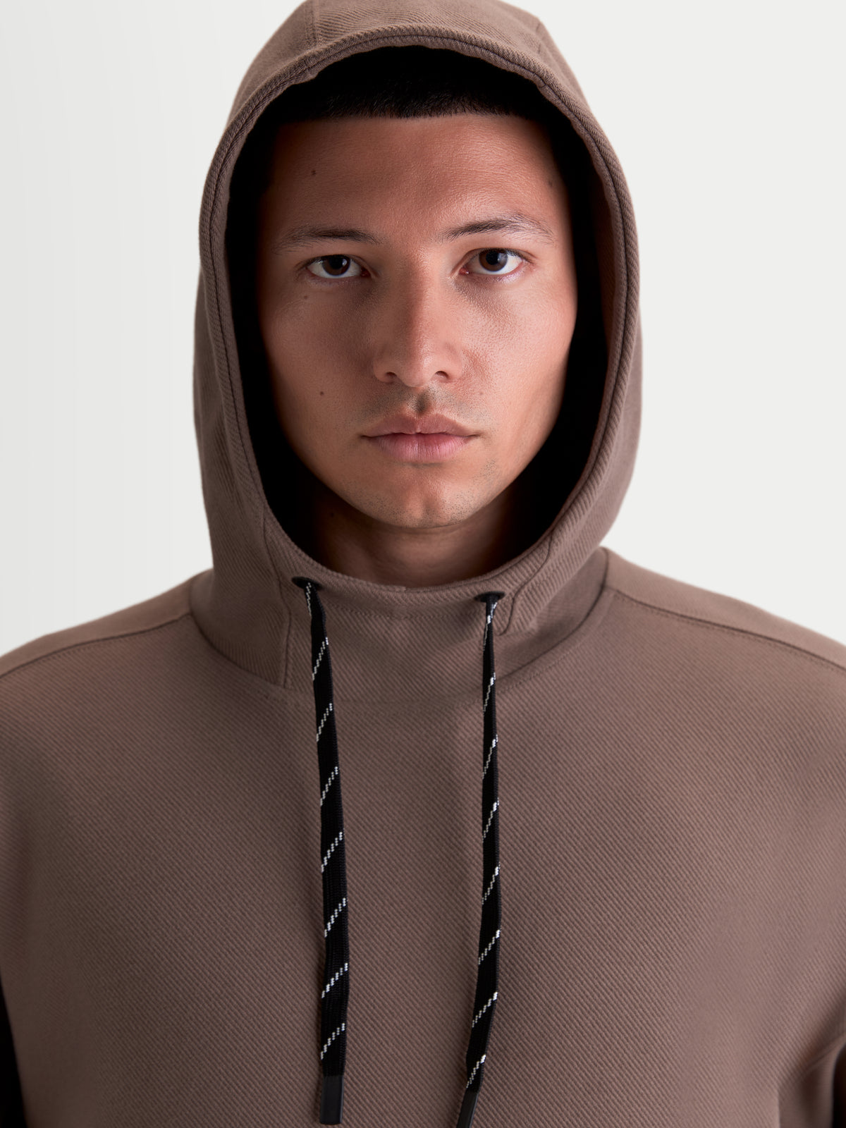 Alpinestars felpa con cappuccio Camino Textured Oversized, felpa sportswear casual unisex, marrone, pile in twill lavorato a maglia testurizzato, collo alto e cappuccio autofoderato, primo piano su modello con cordini a fantasia bianchi e neri.